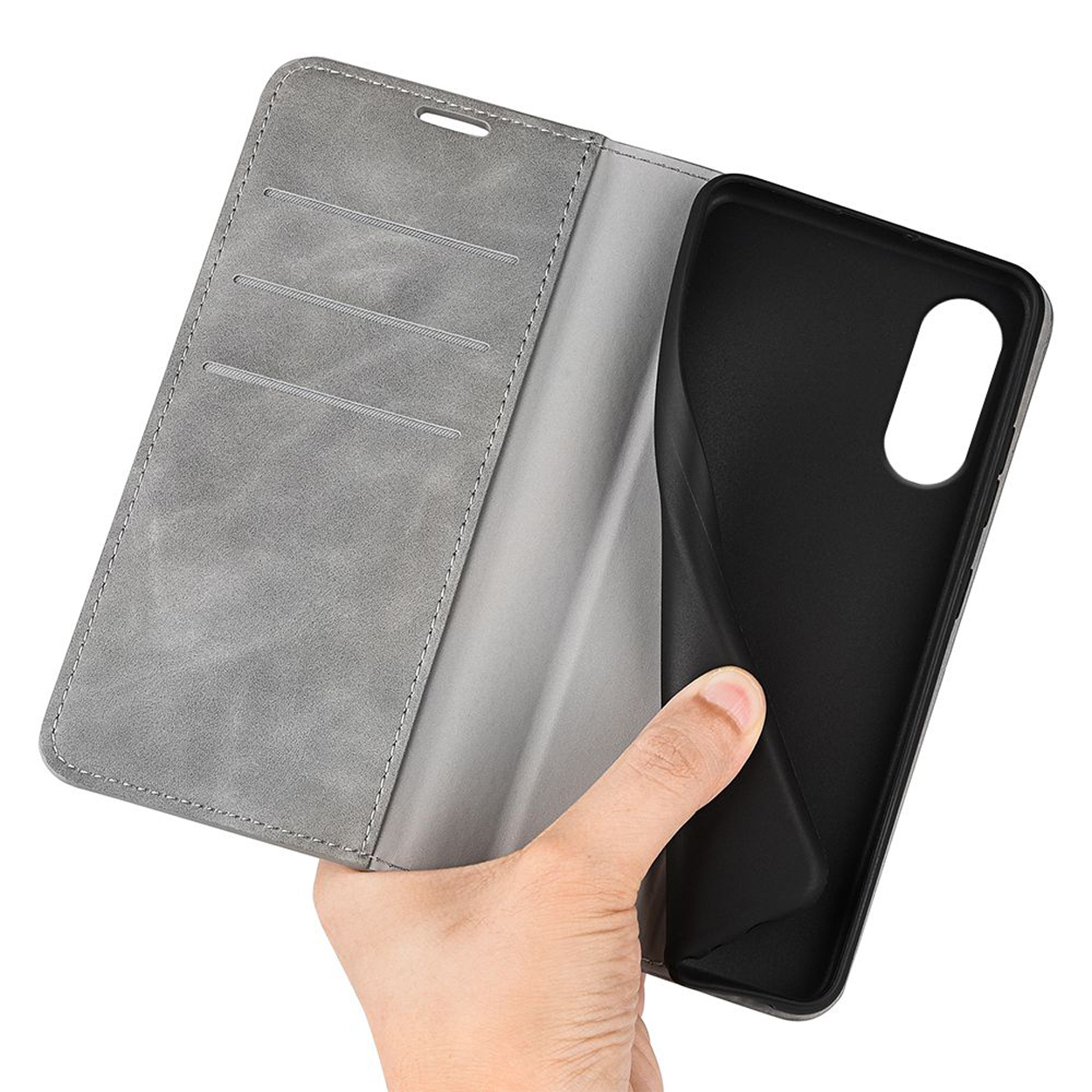 Une main tenant un téléphone. Le téléphone est dans une coque grise.