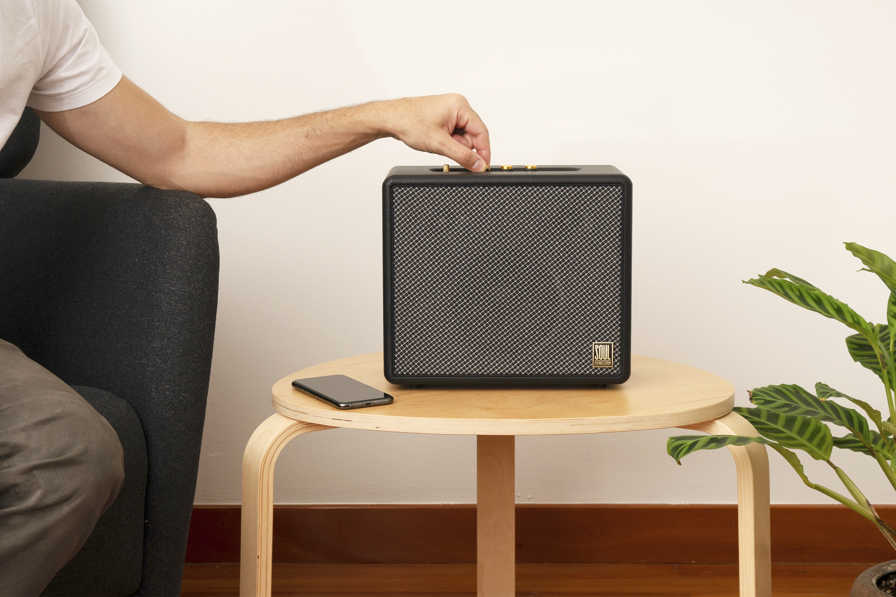 Una mano ajustando la perilla de volumen en un altavoz Marshall negro y dorado.