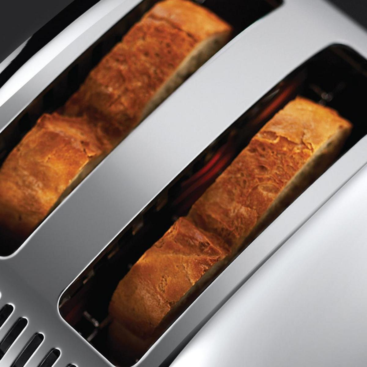 Nahaufnahme eines Toasters mit zwei Toastscheiben. Silbernes Gehäuse, dunkler Innenraum.
