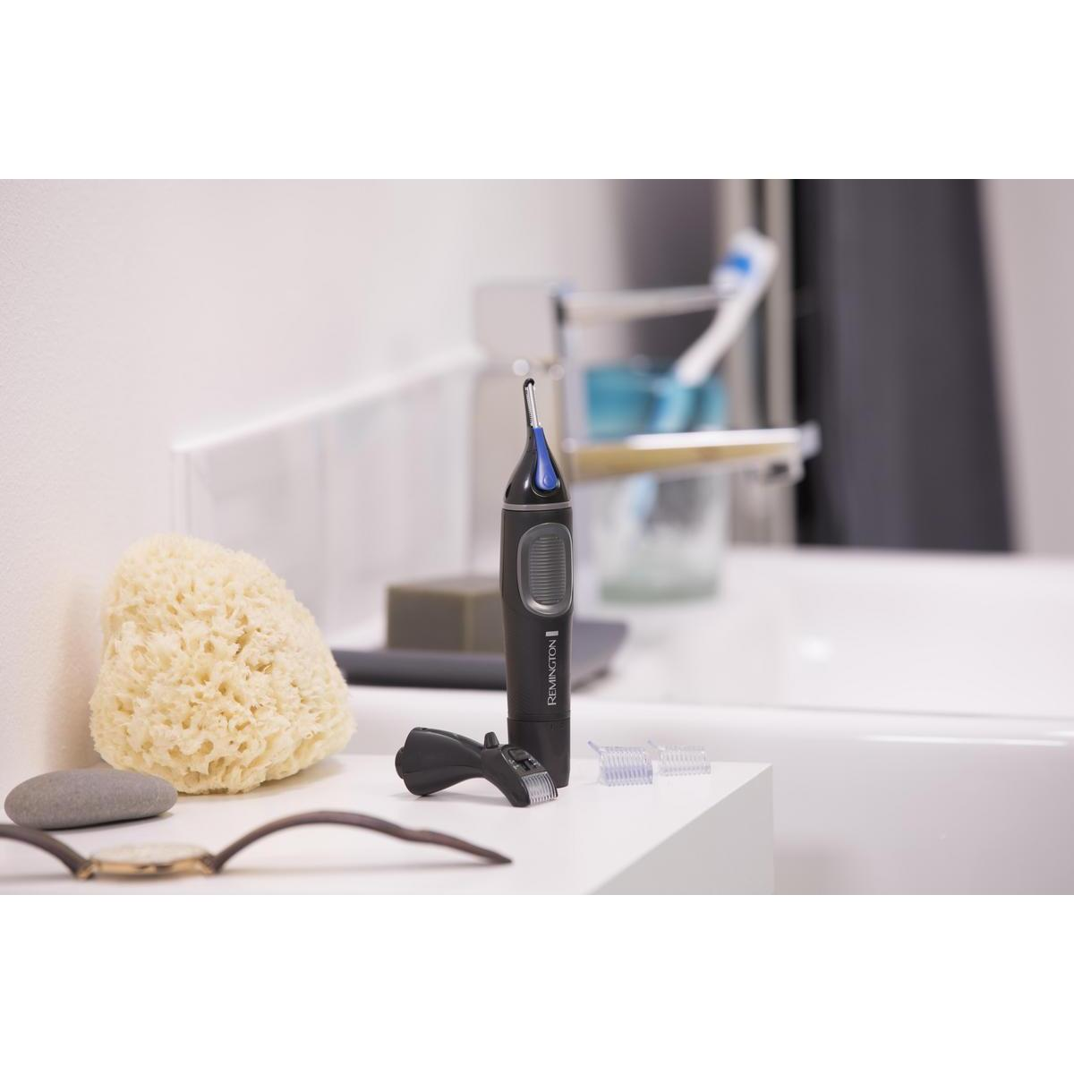 Un ensemble de toilettage sur une surface blanche, comprenant une tondeuse, un miroir, une éponge et des accessoires dans une salle de bain.