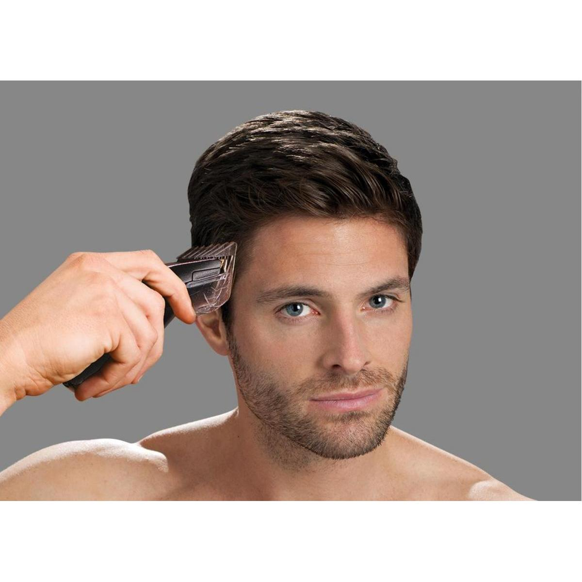 Un uomo con i capelli castani usa un tagliacapelli sul lato della testa.