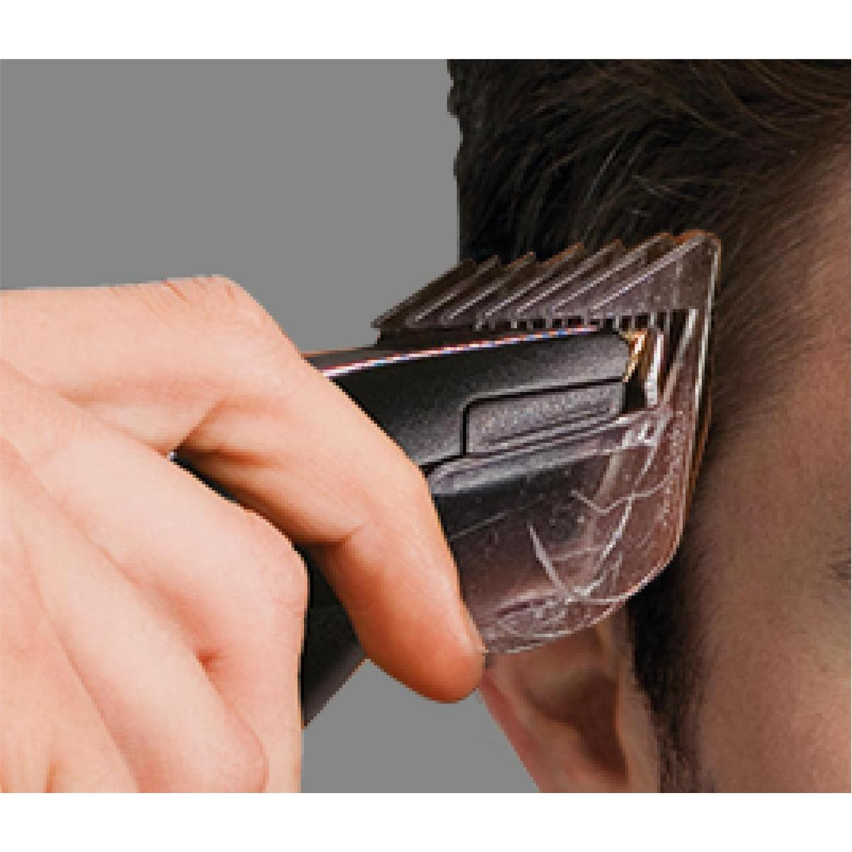 Primo piano di una mano che usa un tagliacapelli sul lato della testa di un uomo.