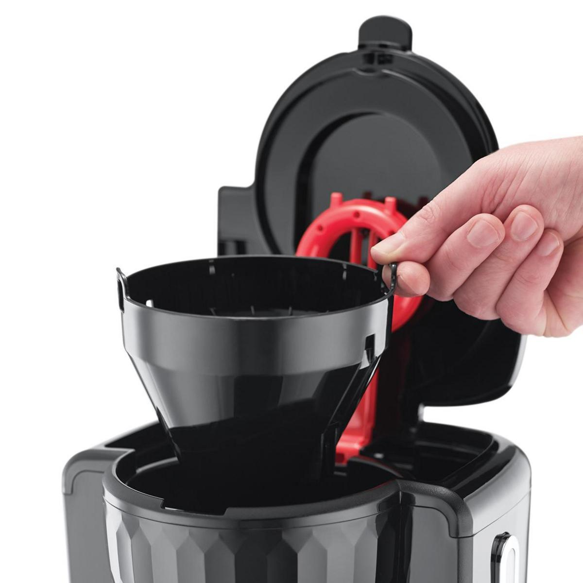 Mano sosteniendo una cesta de filtro negra en una cafetera negra y roja.