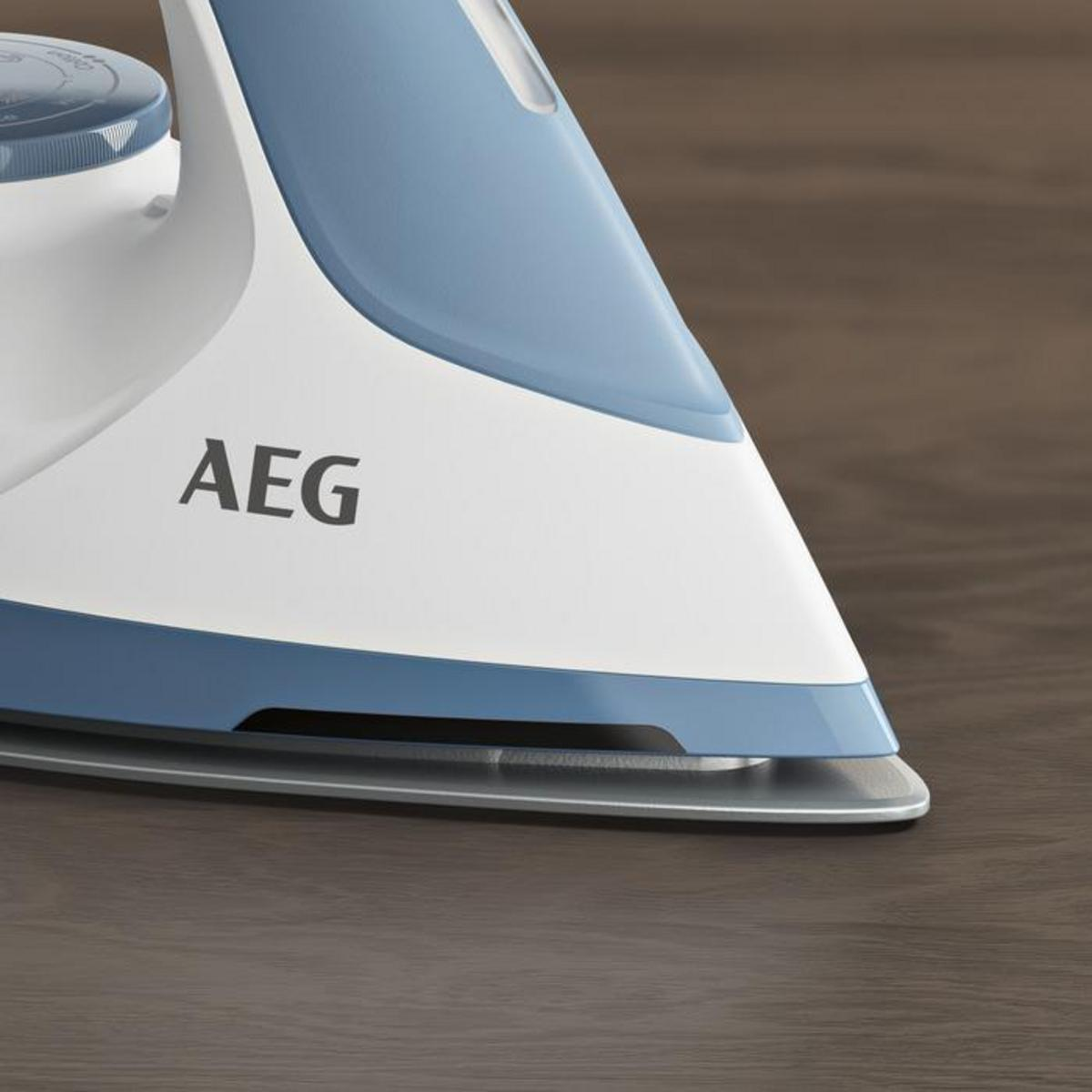Primer plano de una plancha blanca y azul sobre una superficie de madera. La marca "AEG" es visible en la superficie de la plancha.
