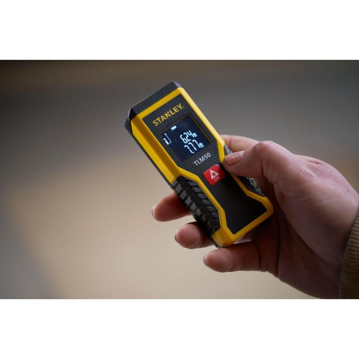 Medidor láser de distancia amarillo y negro, dispositivo de medición, en mano.