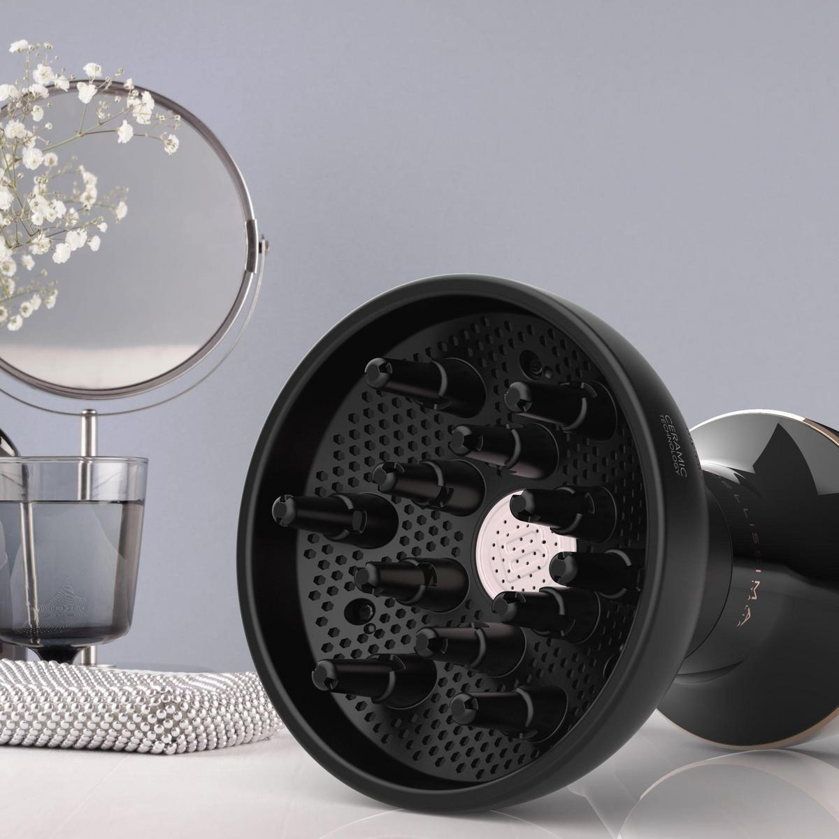 Czarny dyfuzor do suszarki do włosów z wieloma dyszami, lustro i kwiaty na szarym tle.