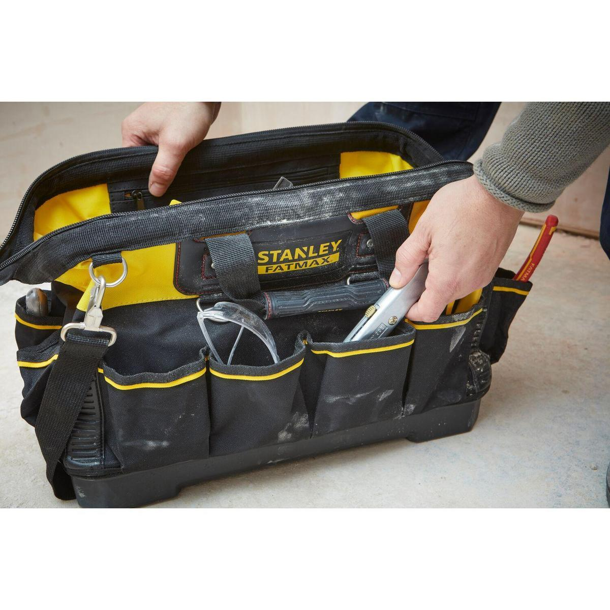 Hände einer Person, die eine offene, schwarz-gelbe Stanley Fatmax Werkzeugtasche halten.