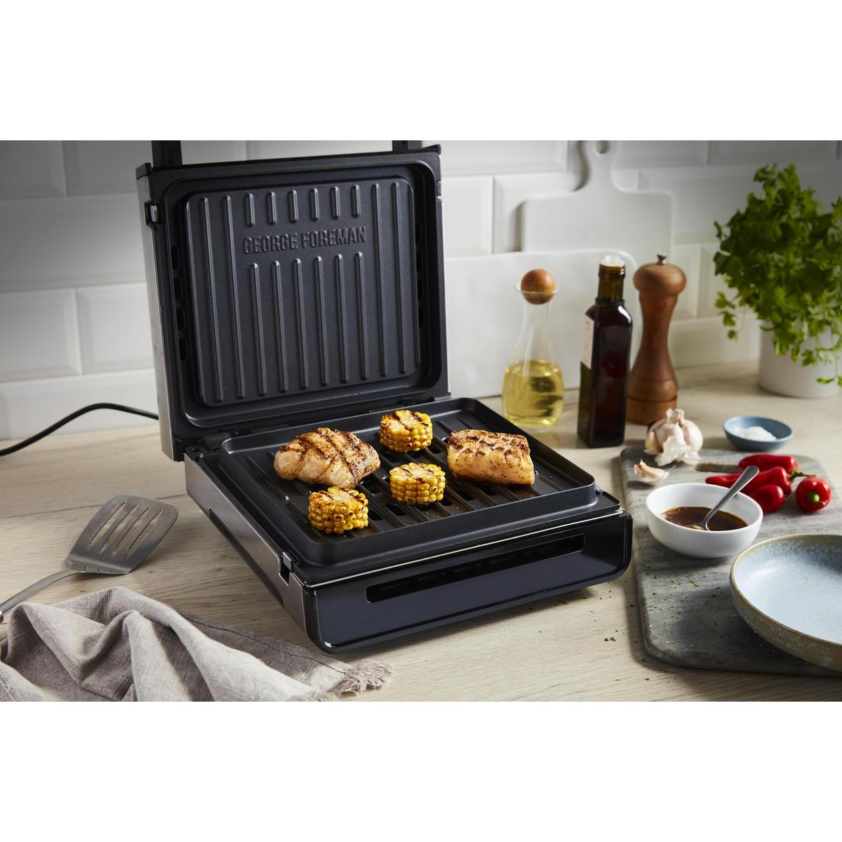 Grill George'a Foremana z grillowanym jedzeniem, w tym kukurydzą i mięsem, na drewnianej powierzchni.