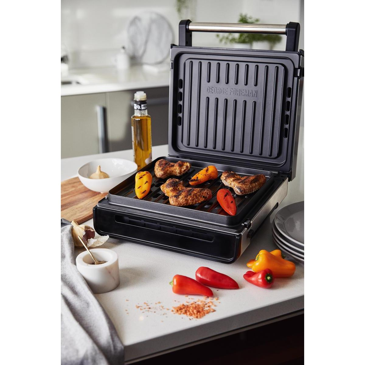 Grill George Foreman z ugotowanym jedzeniem. Papryka i olej na blacie.