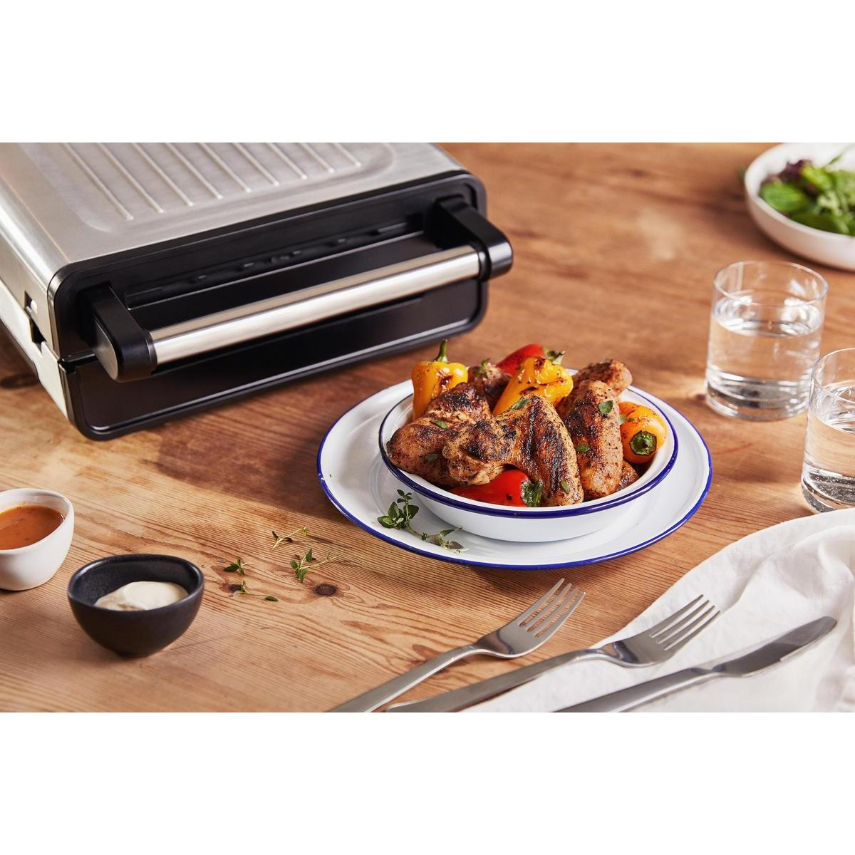 Grillowane jedzenie z warzywami podane na talerzu. Stół z sosami i widelcami. Przygotowanie.