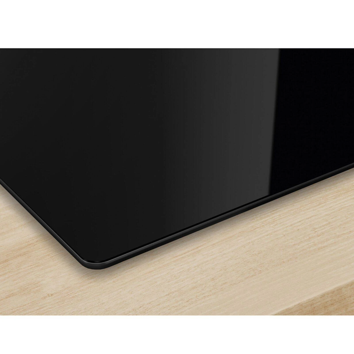Un primo piano di un piano cottura a induzione nero su una superficie in legno chiaro.