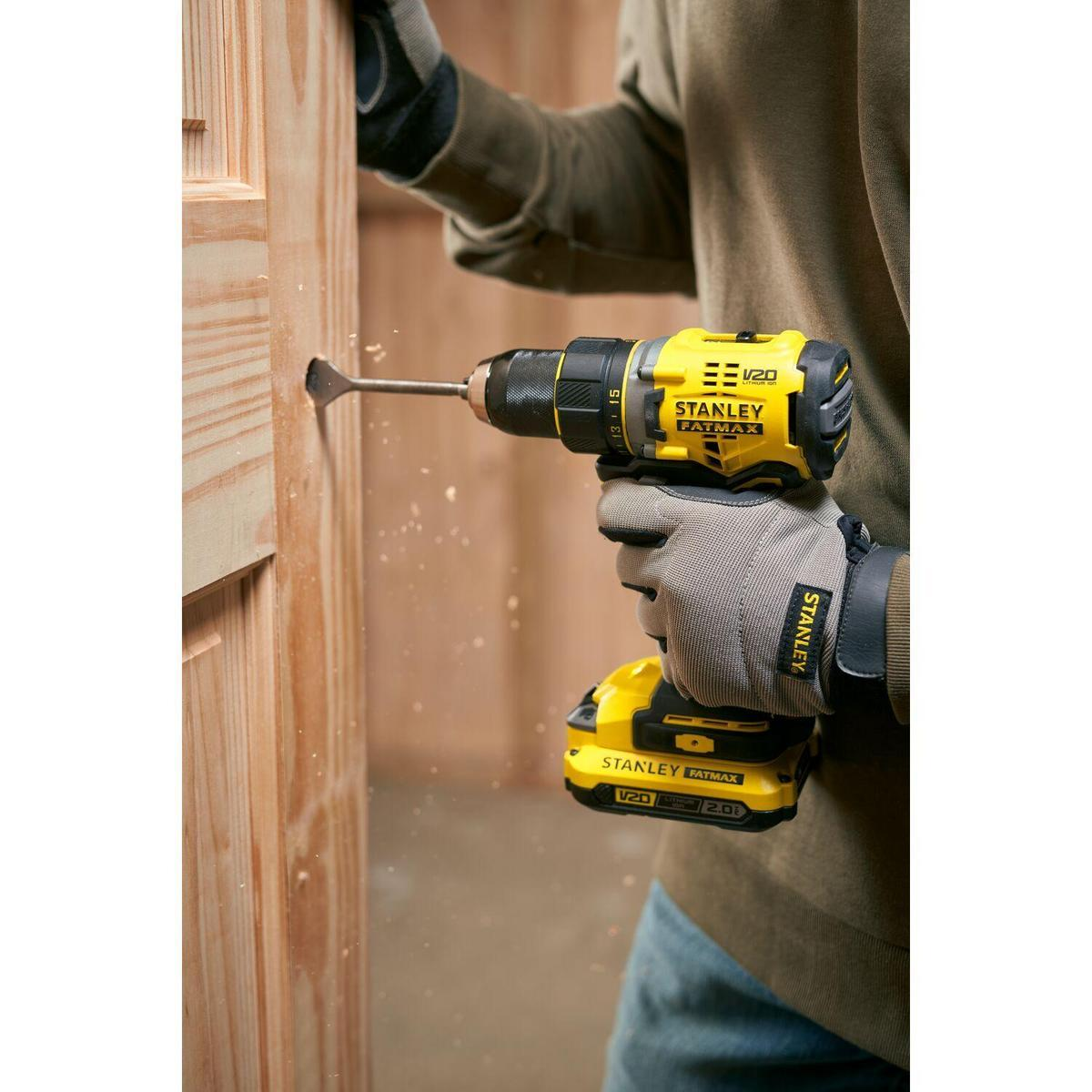 Una persona taladra una puerta de madera con un taladro eléctrico amarillo y negro.