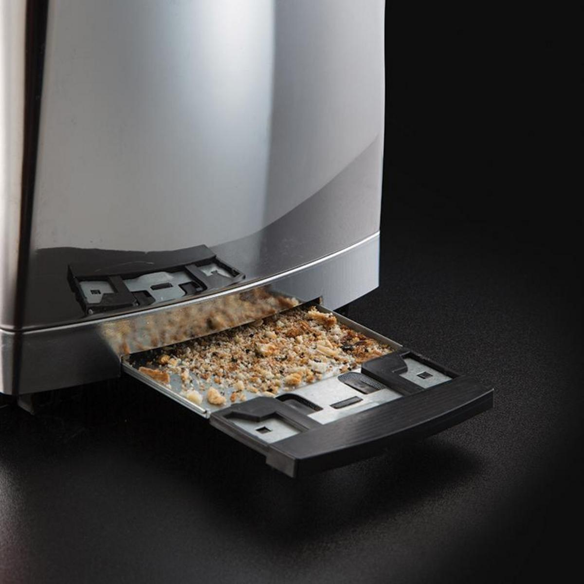 Nahaufnahme eines Toasters mit herausgezogener Krümelschublade, die Brotkrumen zeigt.