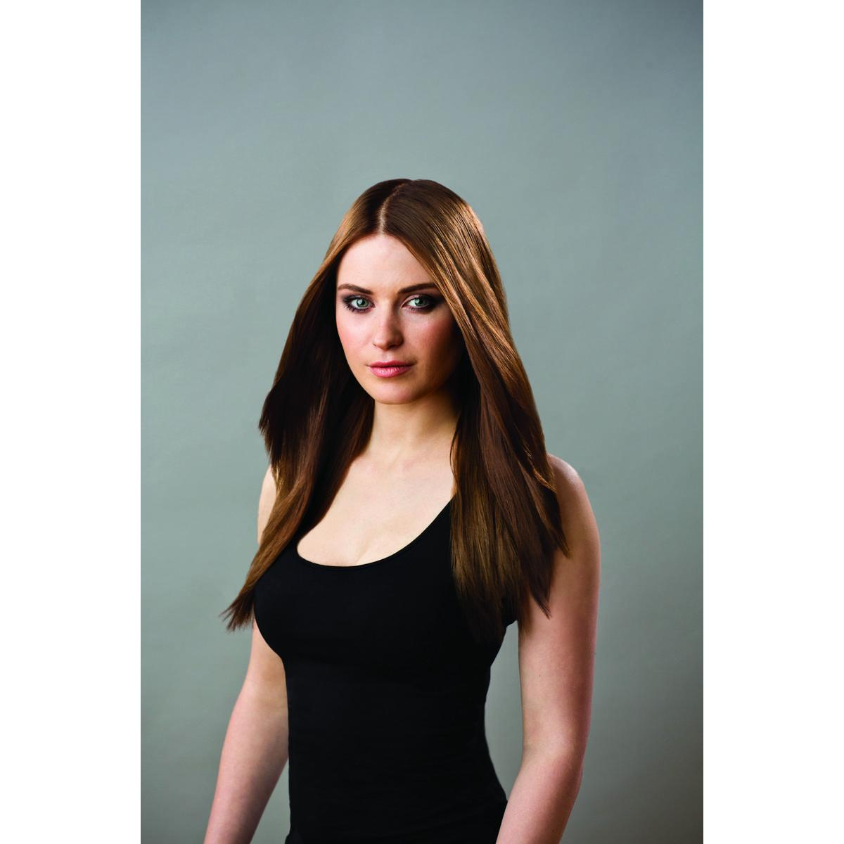 Une femme aux longs cheveux bruns portant un débardeur noir, regardant la caméra.