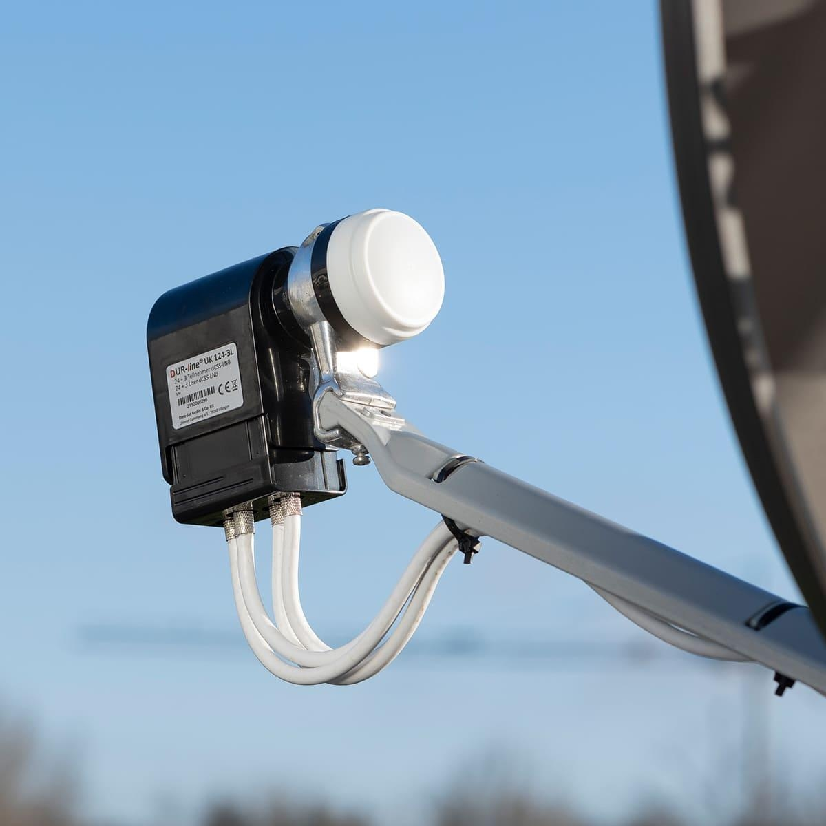 Satellitenschüssel LNB, mit Kabeln, vor blauem Himmel.