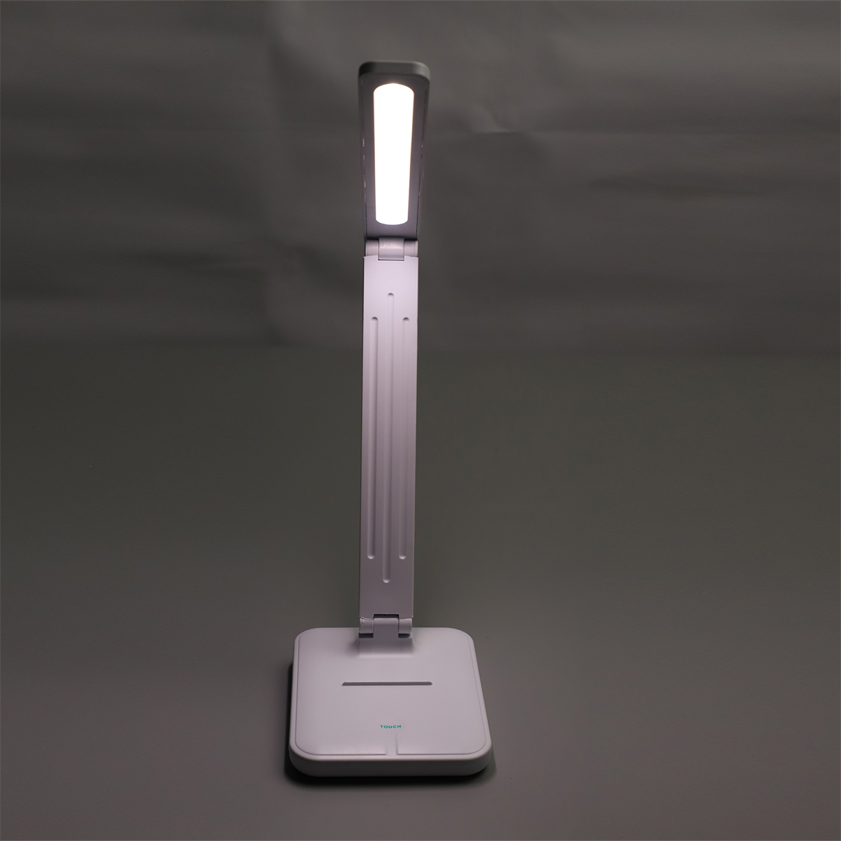 Eine weiß-graue Schreibtischlampe mit LED-Licht auf grauer Oberfläche.
