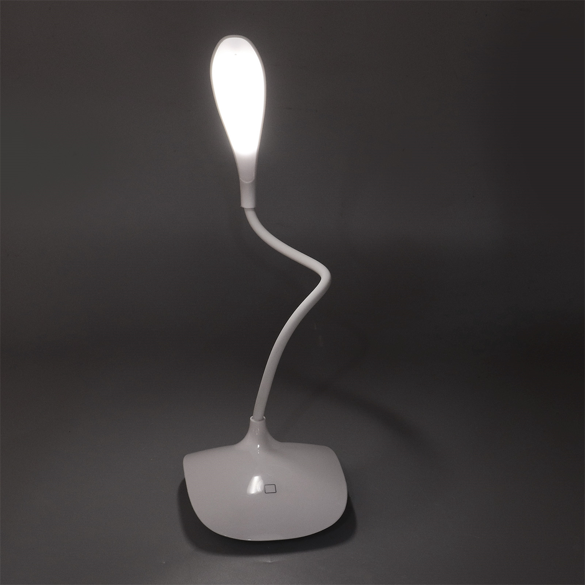 Eine weiße Schreibtischlampe mit Schwanenhals leuchtet auf einer grauen Oberfläche. Die Lampe hat einen flexiblen Hals.