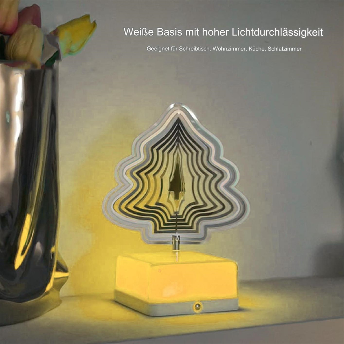 Eine silberne dekorative Lampe mit gelbem Sockel und eine Vase im Hintergrund.