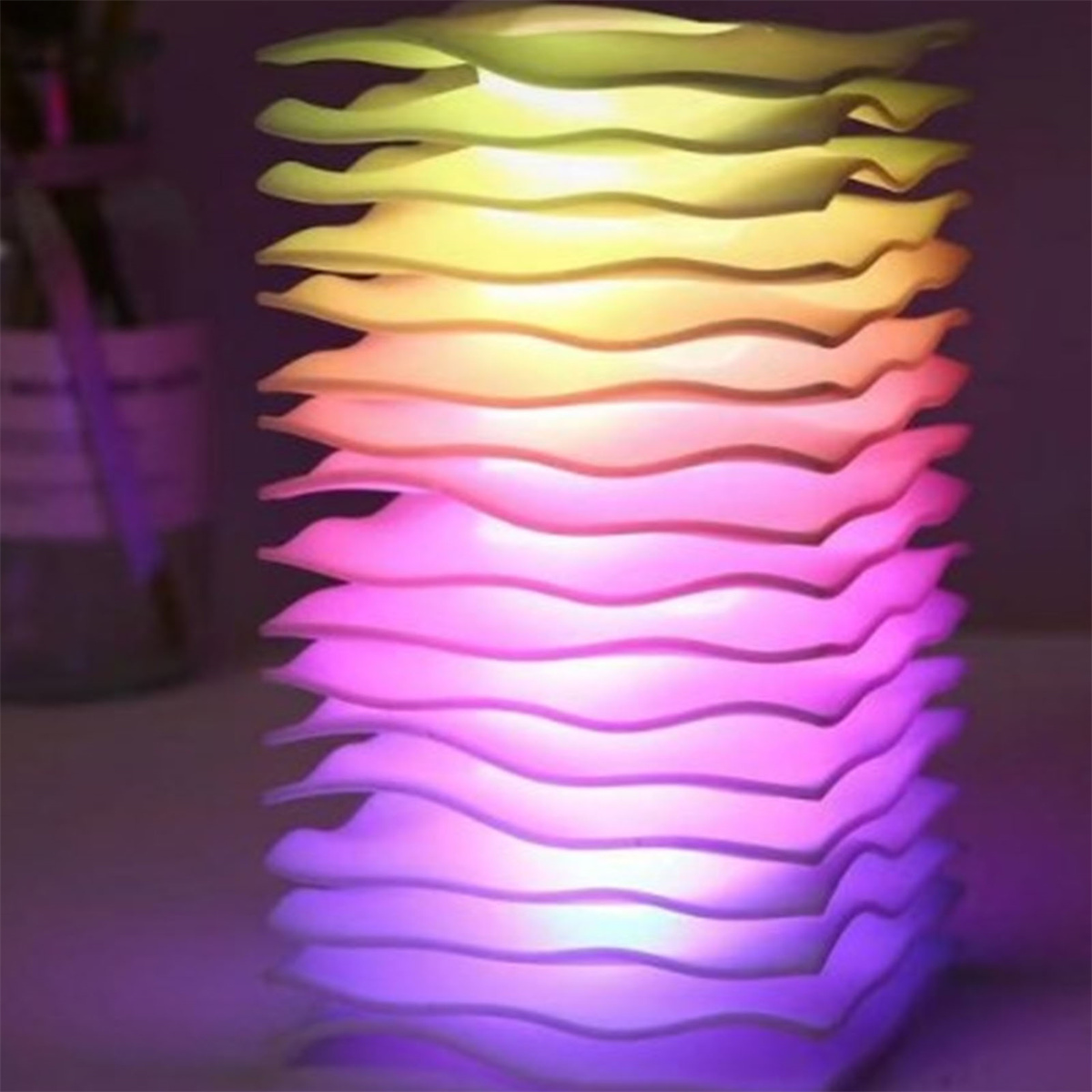 Eine stapelbare Lampe mit wellenförmigem Design. Farben wechseln von Gelb zu Rosa.