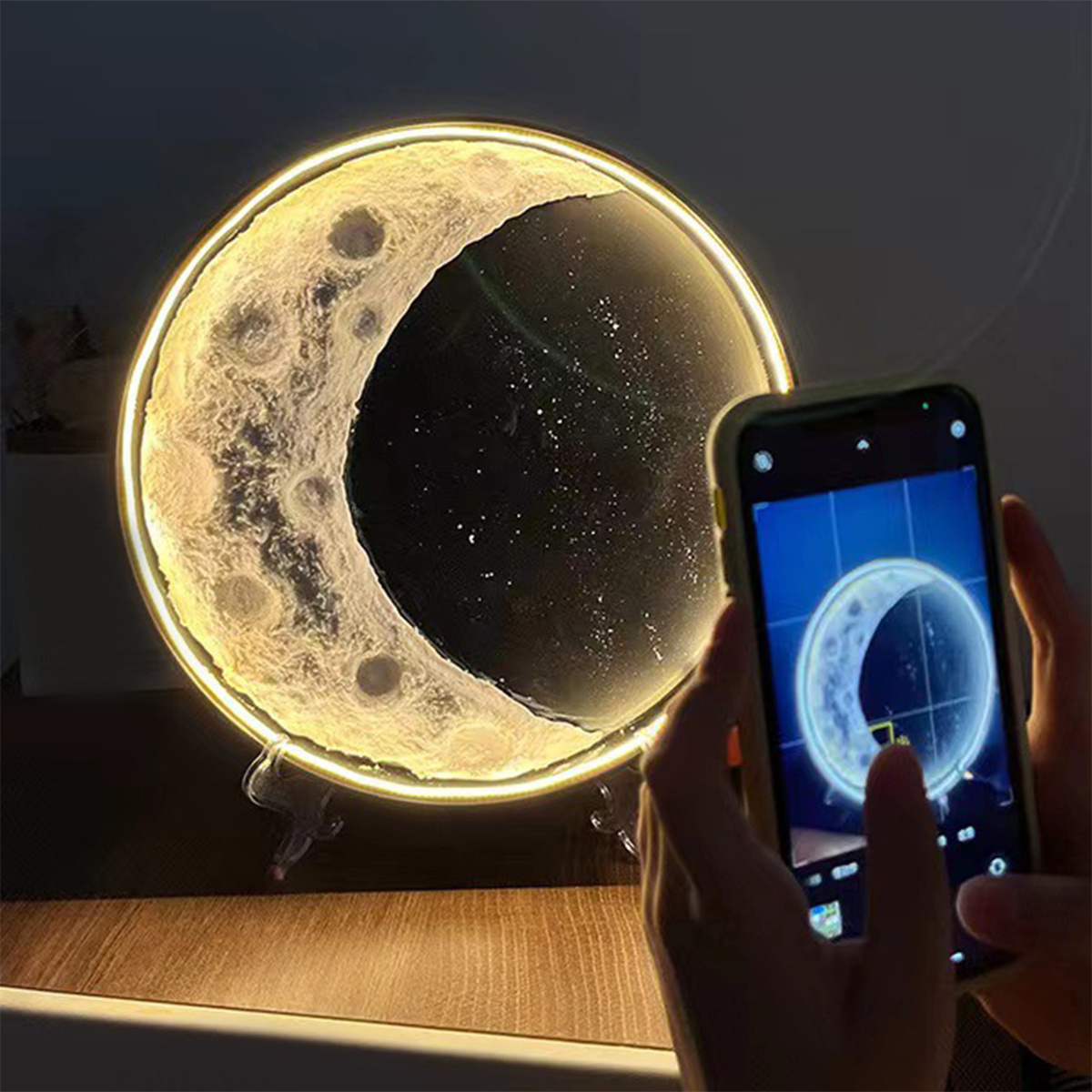 Ein beleuchtetes Mondkunstwerk, mit einer Person, die ein Foto mit einem Telefon macht.
