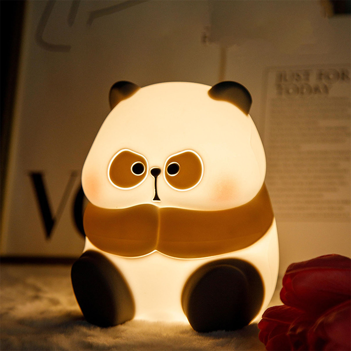 Panda-Lampe, die auf dunklem Hintergrund leuchtet. Der Panda hat braune Augen und ein braunes Band.