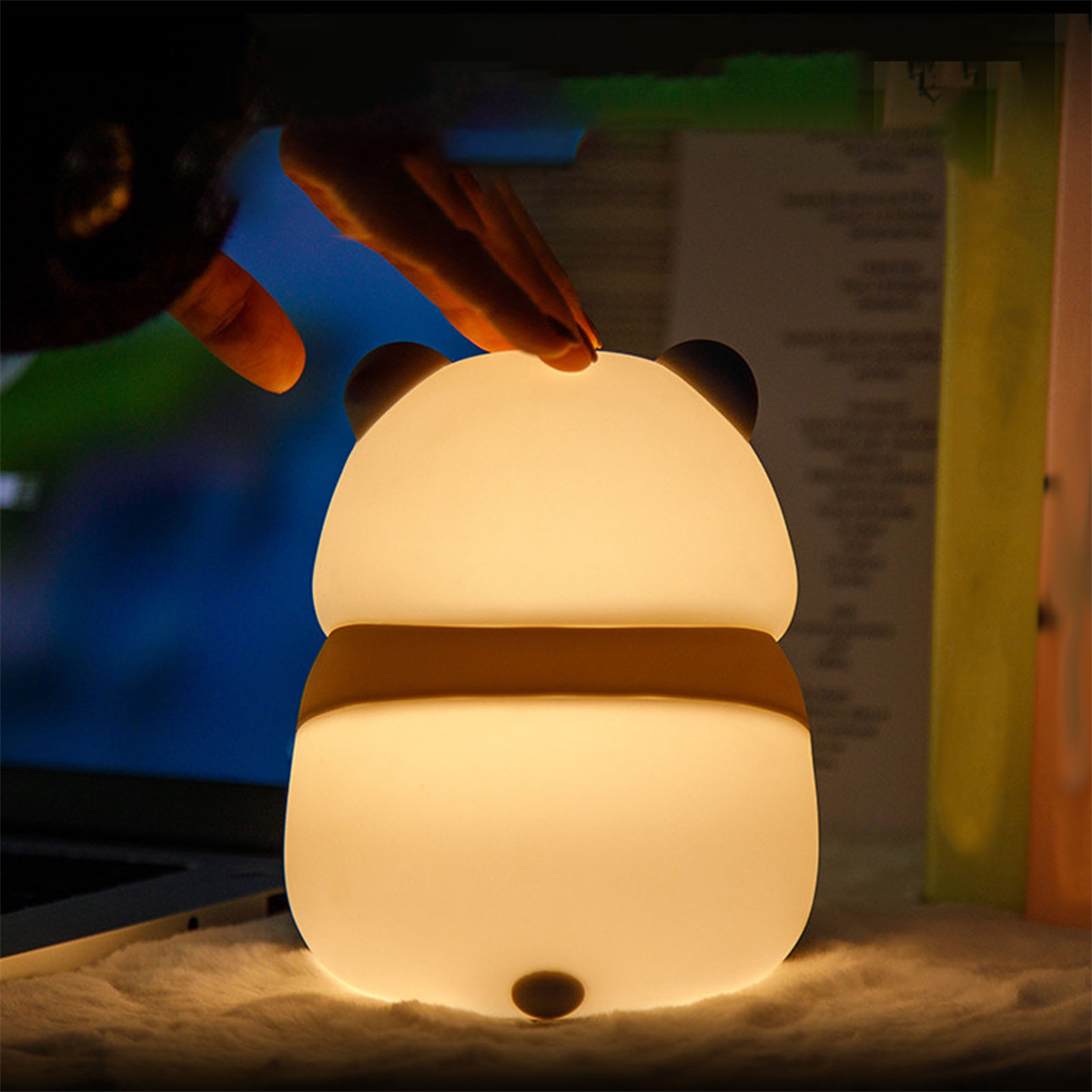 Ein niedliches, pandaförmiges Nachtlicht leuchtet. Eine Hand berührt die Oberseite des Lichts.
