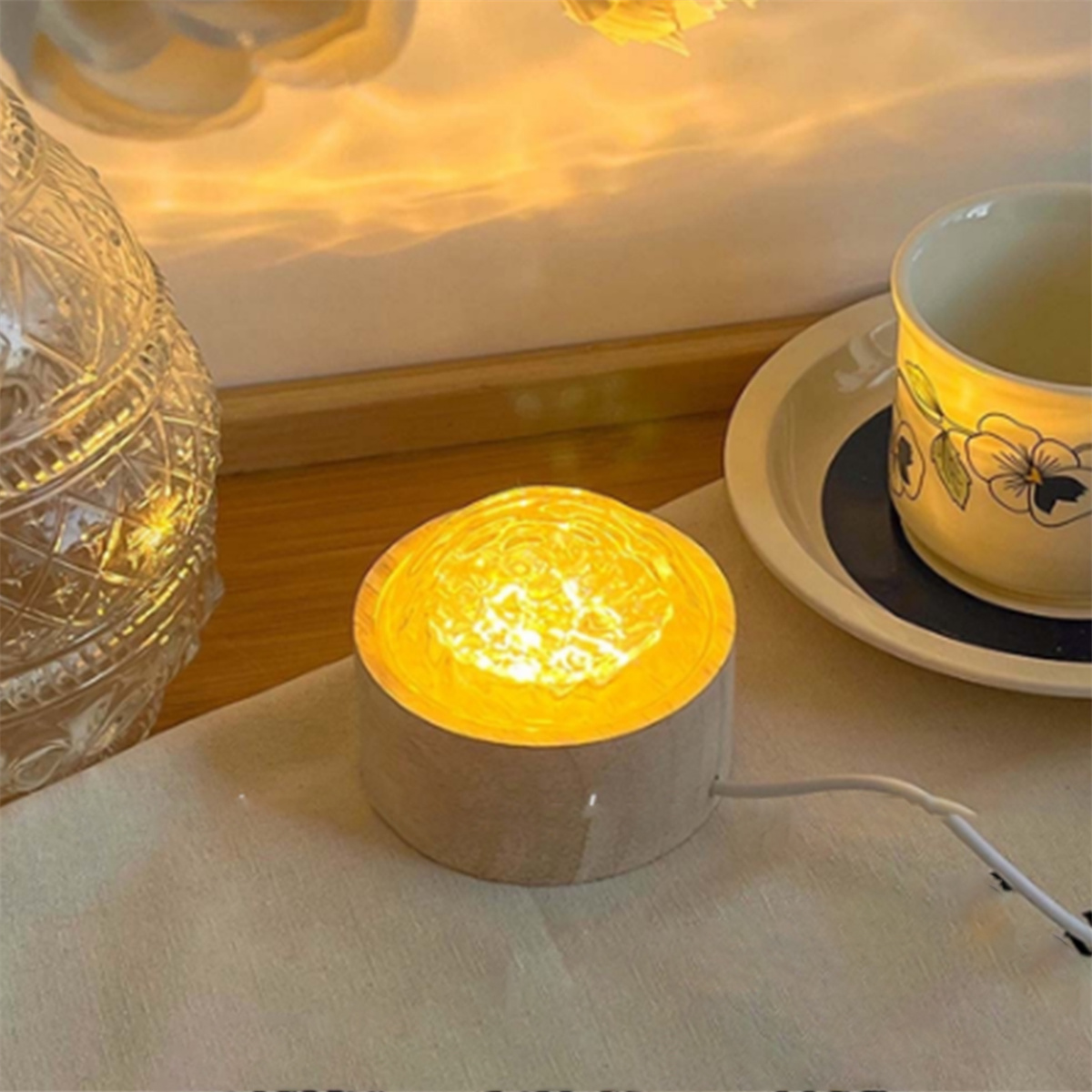 Gelbe Lampe, Teller mit Tasse und Glasvase auf Tisch.