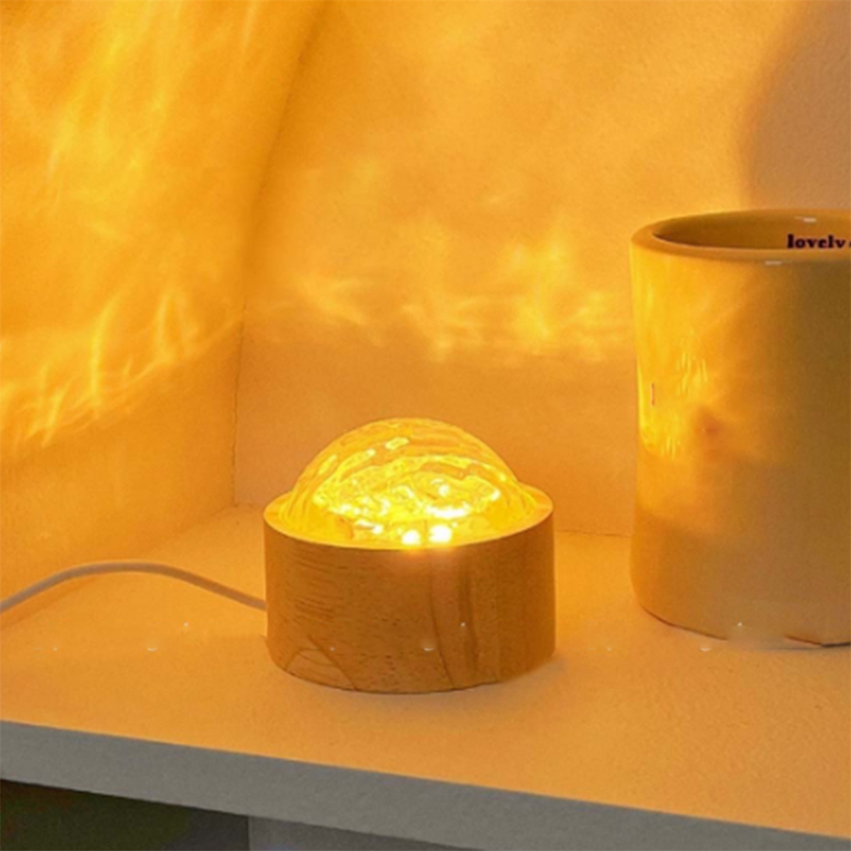 Eine Lampe mit Holzsockel mit leuchtendem Licht auf einem Tisch, wirft Licht auf die Wand.