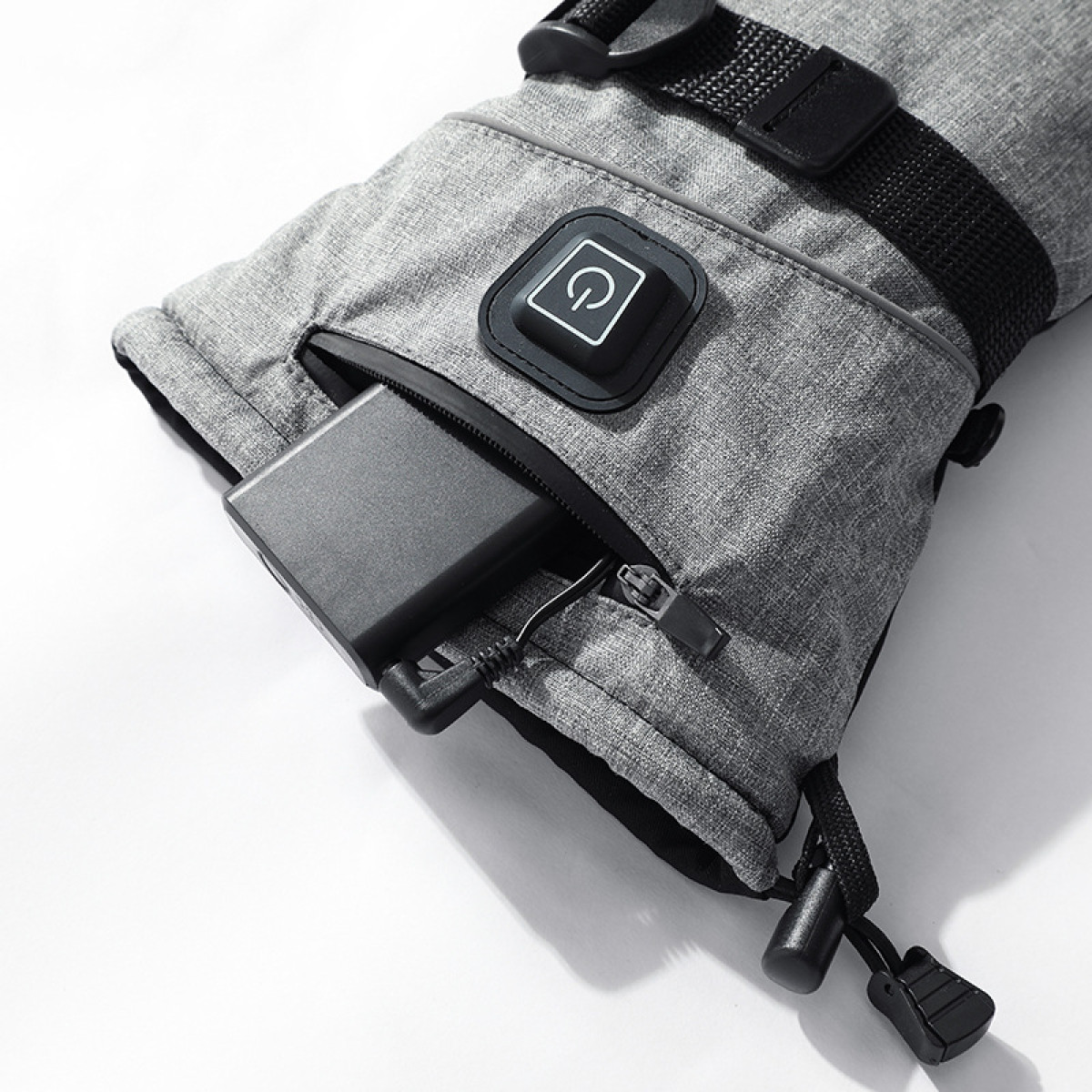 Beheizter Handschuh mit Batterietasche. Der Handschuh ist grau. Ein Knopf ist außen.