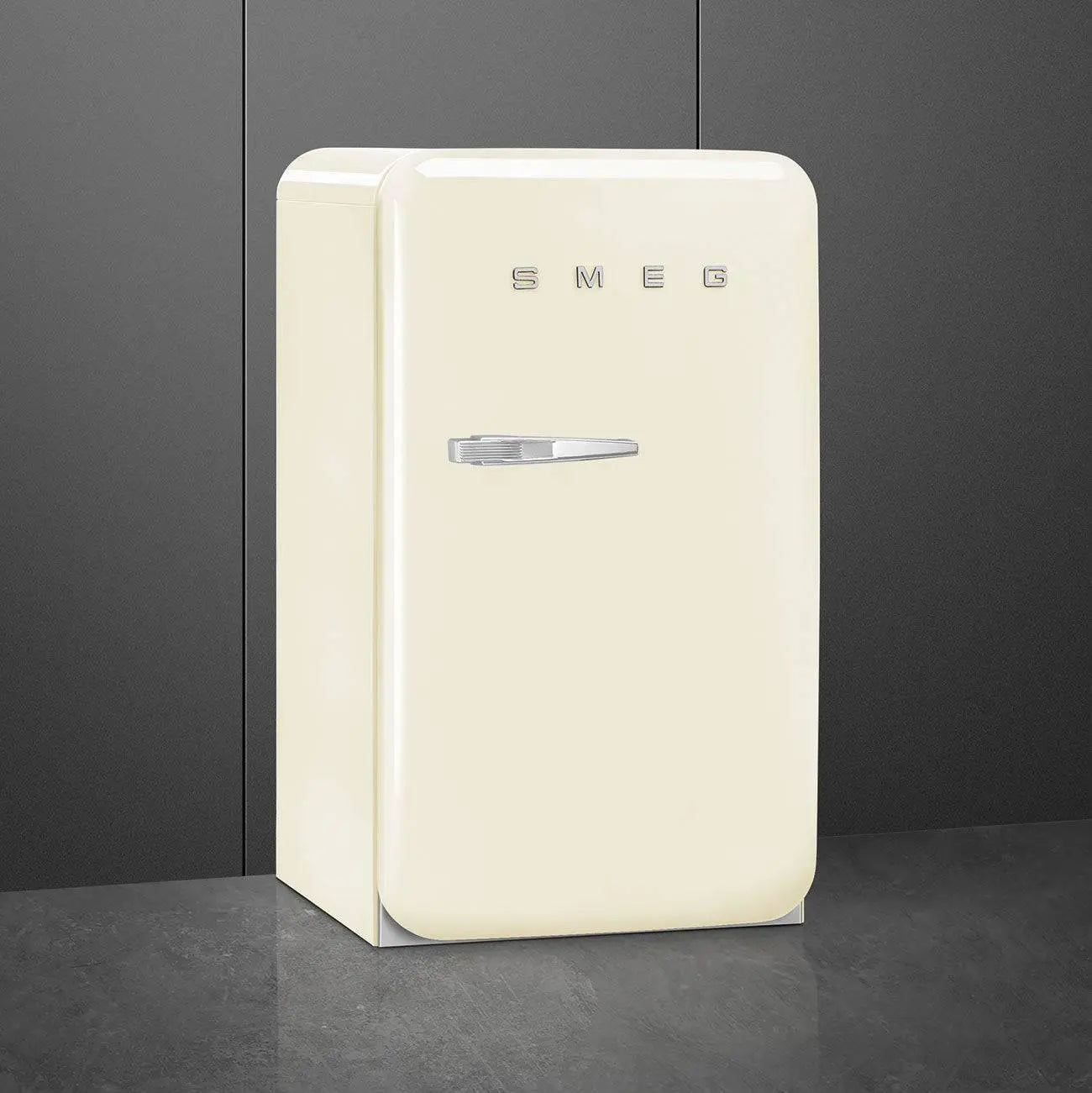 Un refrigerador SMEG color crema contra una pared gris oscuro.