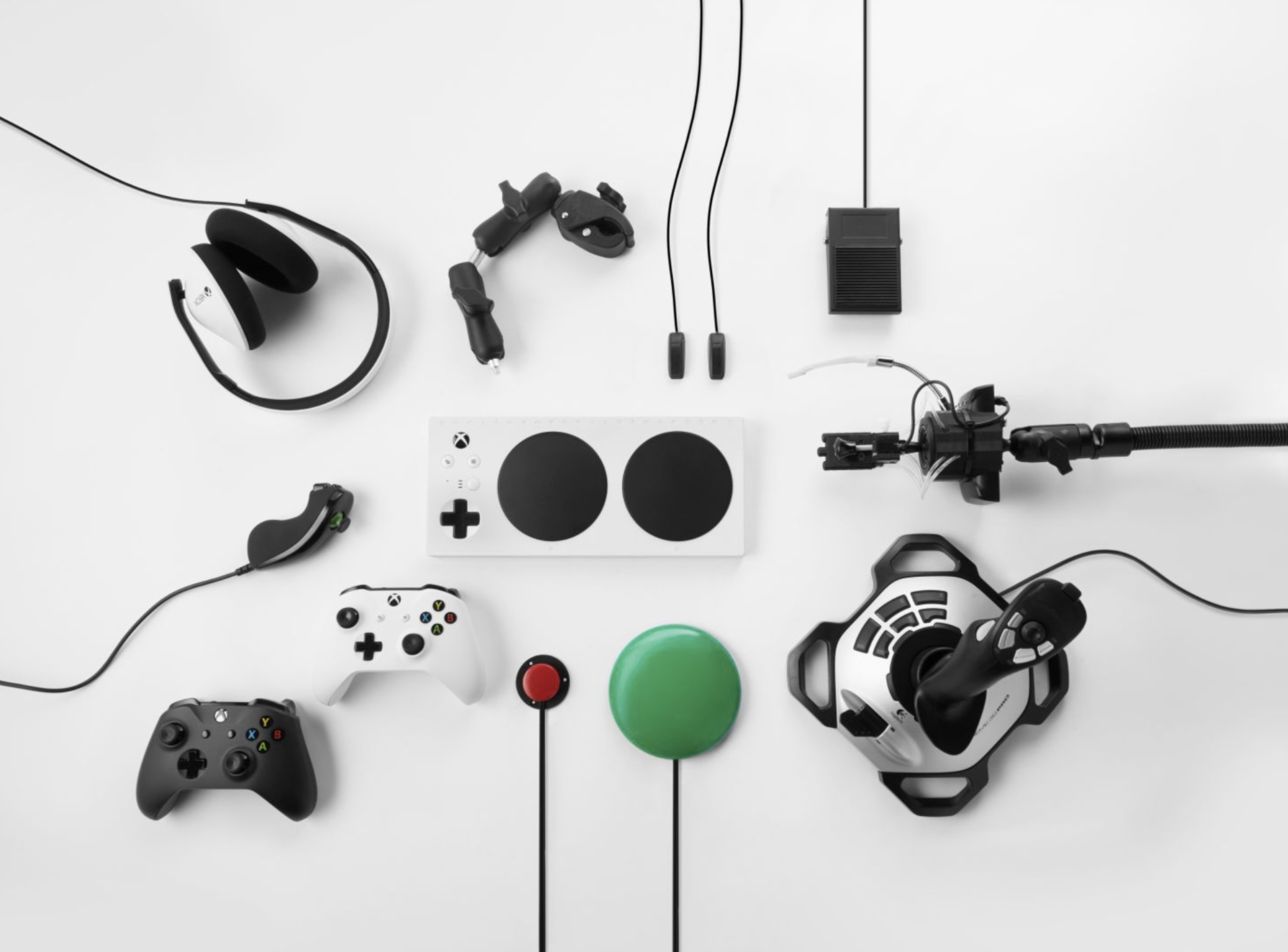 Assortimento di accessori per gaming Xbox su superficie bianca, inclusi controller, cuffie e pulsanti.