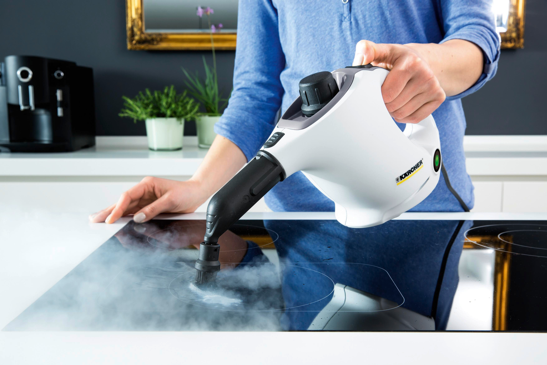 Osoba używająca białego parowego środka czyszczącego Kärcher na czarnej płycie grzejnej. Widoczna para.