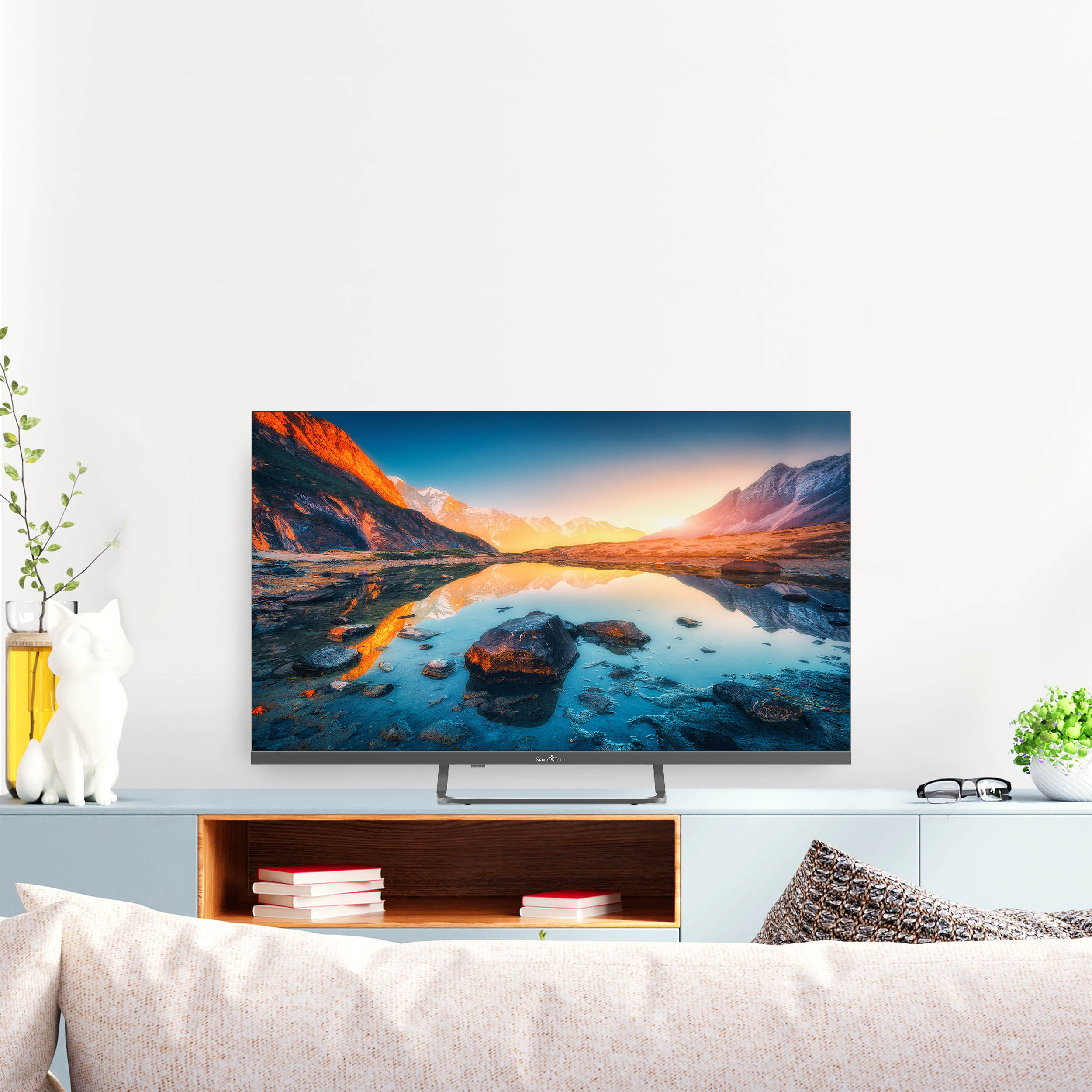 Duży telewizor z płaskim ekranem wyświetlający zachód słońca nad górami odbijającymi się w wodzie.
