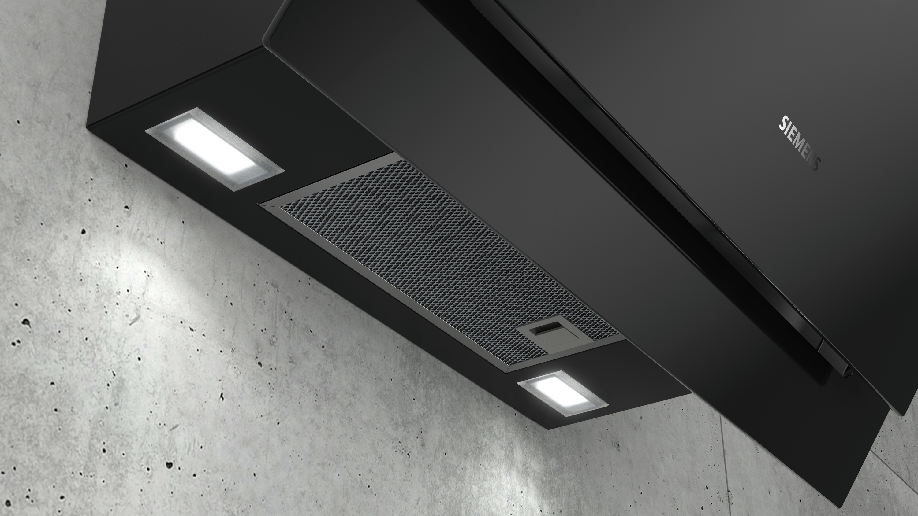 Black range hood with two lights and a silver filter, mounted on a concrete wall.