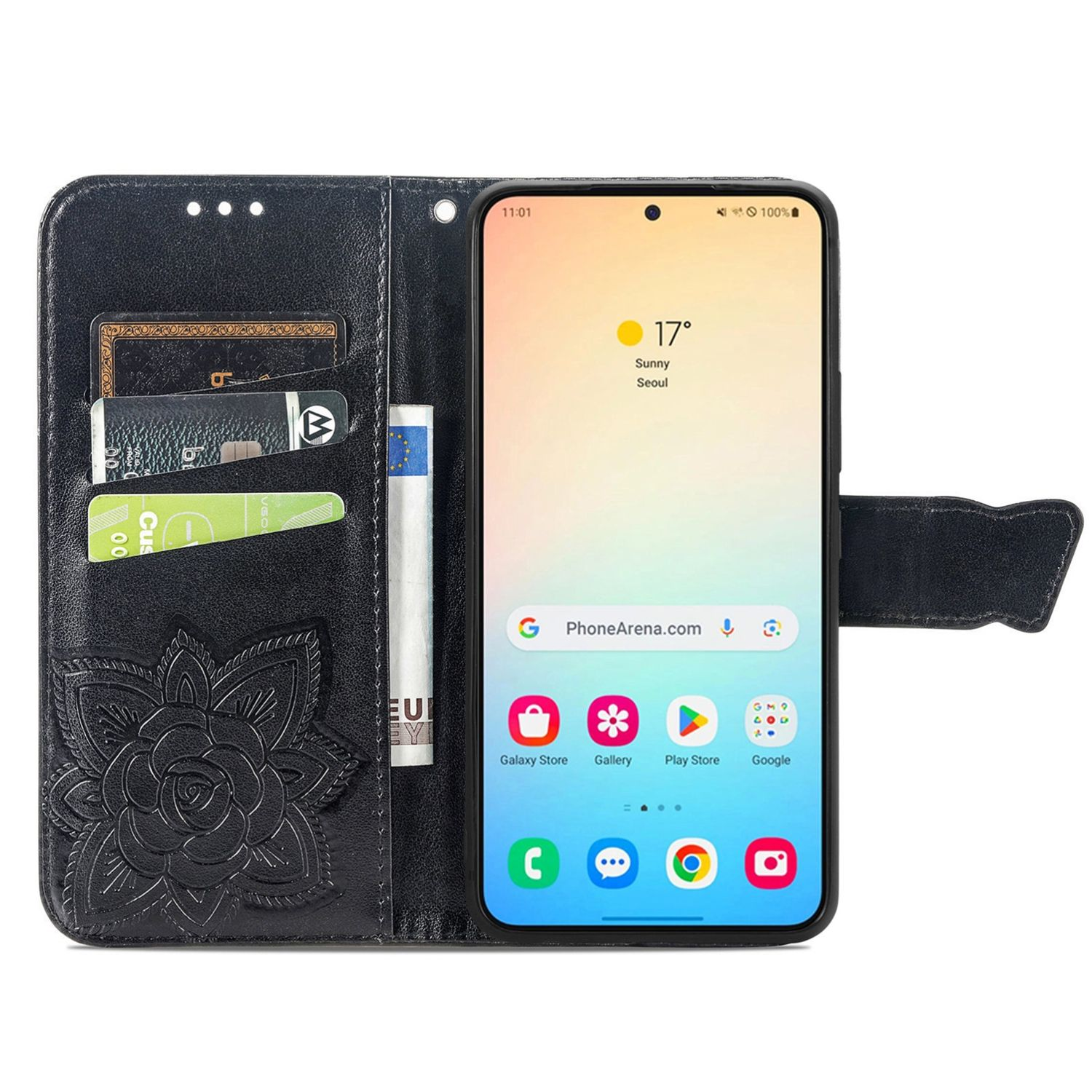 Funda de teléfono negra con diseño floral y ranuras para tarjetas. Un teléfono muestra un día soleado.