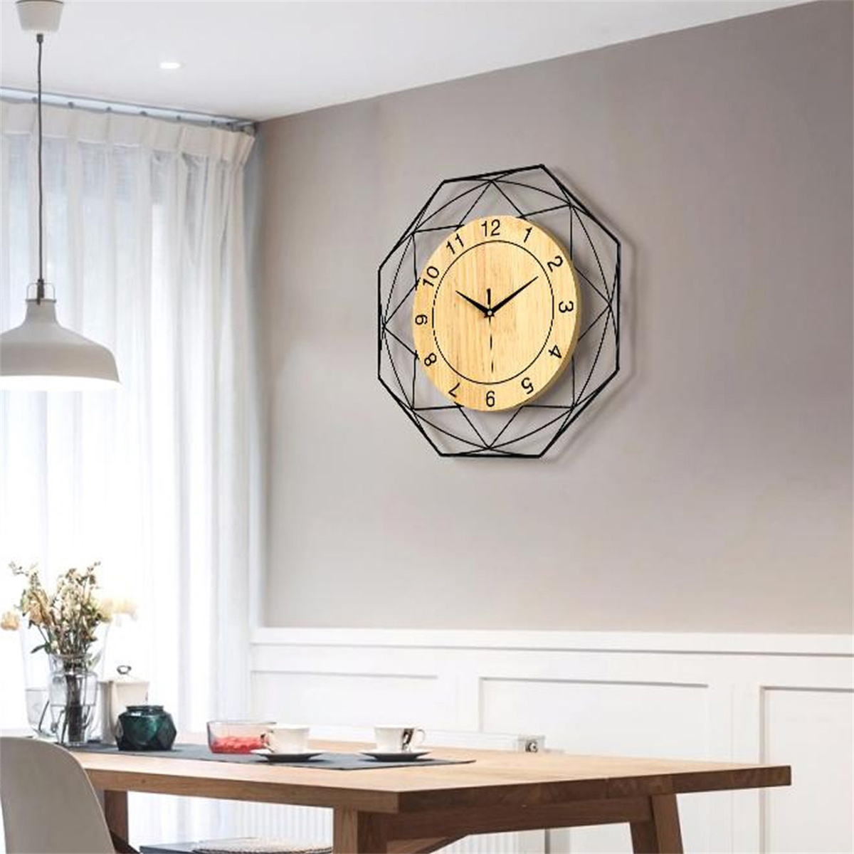 Holz- und schwarze geometrische Uhr an grauer Wand, mit Esstisch.