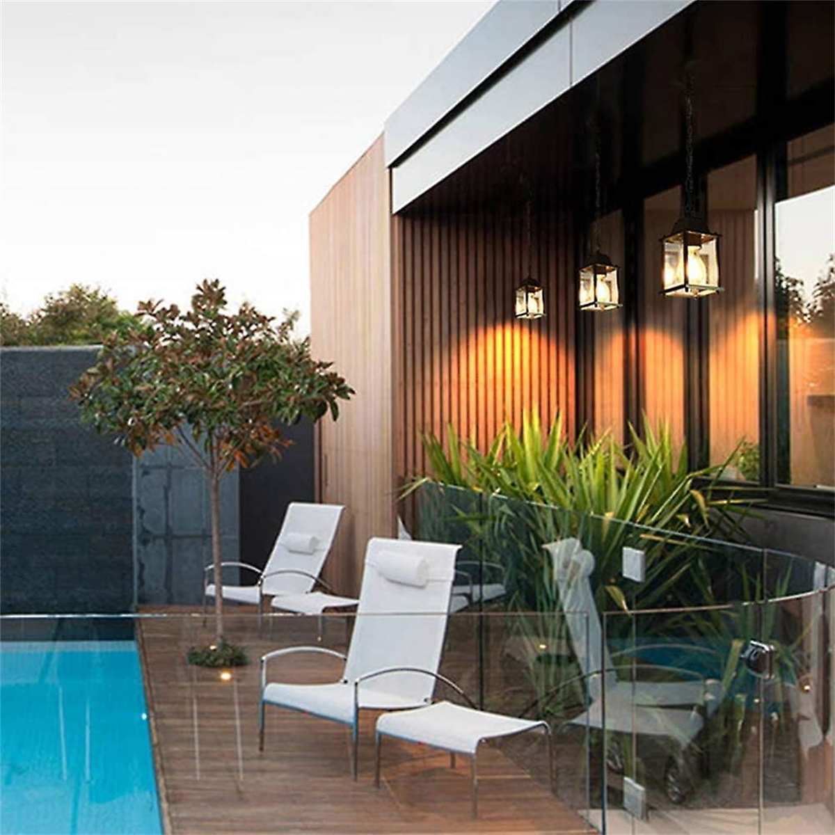 Terrasse im Freien mit Stühlen, Pool und Hängelampen. Das Gebäude hat Holzverkleidung.