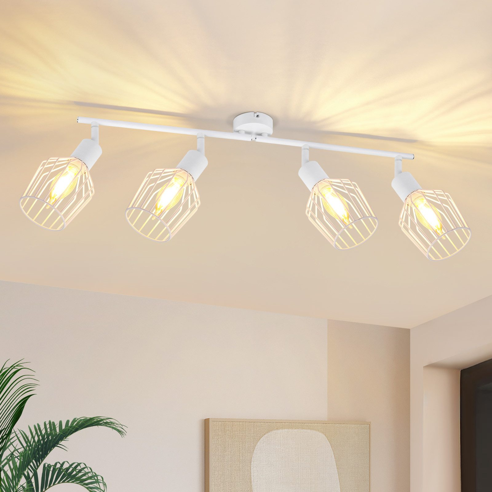 Quattro faretti bianchi su una barra bianca, montati su un soffitto bianco. La luce brilla.