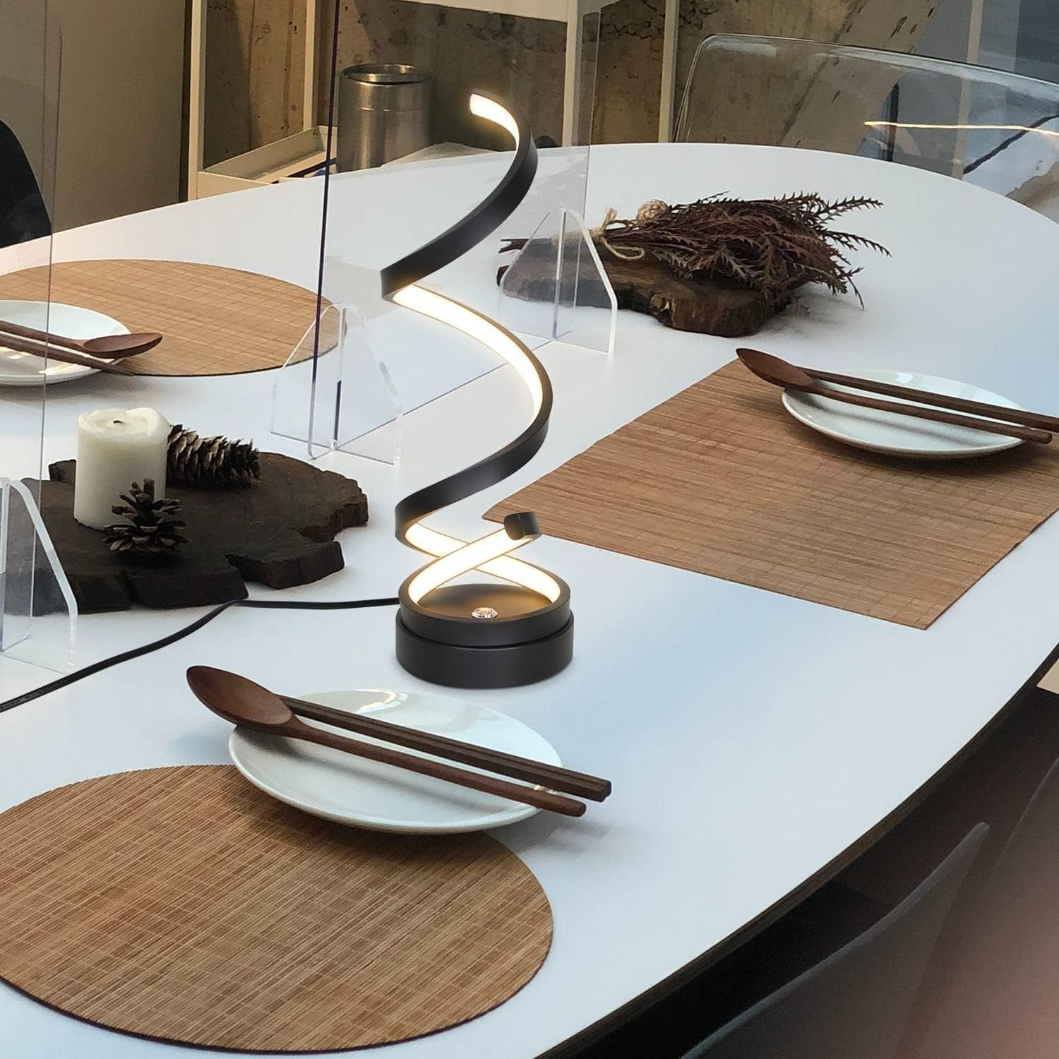 Nakrycie stołu z lampą spiralną pośrodku, dwoma talerzami z pałeczkami i innymi dekoracjami.