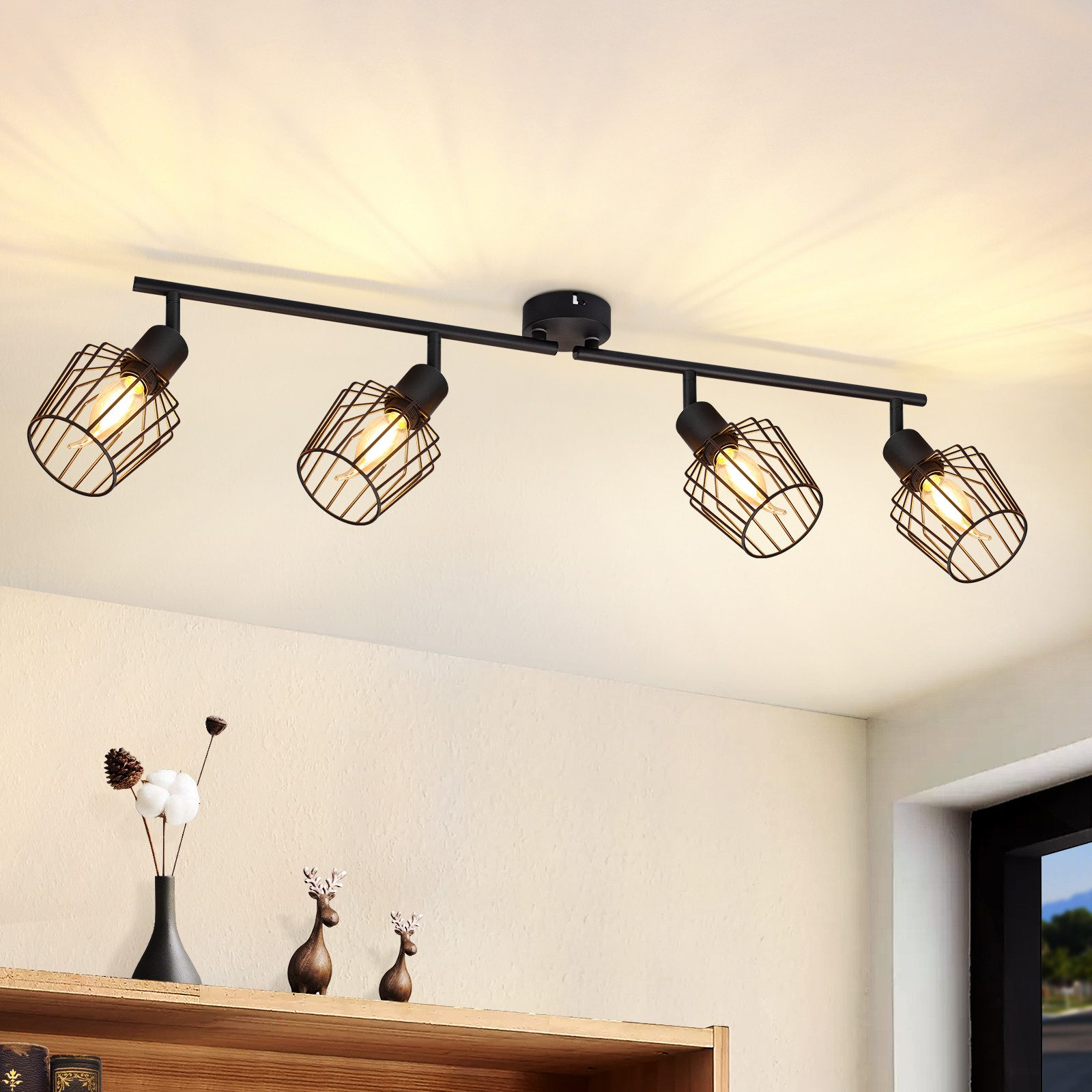 Quattro faretti neri su una barra nera, appesi al soffitto. Le luci sono in gabbie con una lampadina.