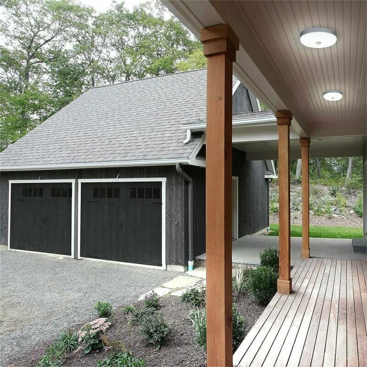Ein Haus mit Garage und überdachter Veranda mit Holzsäulen.