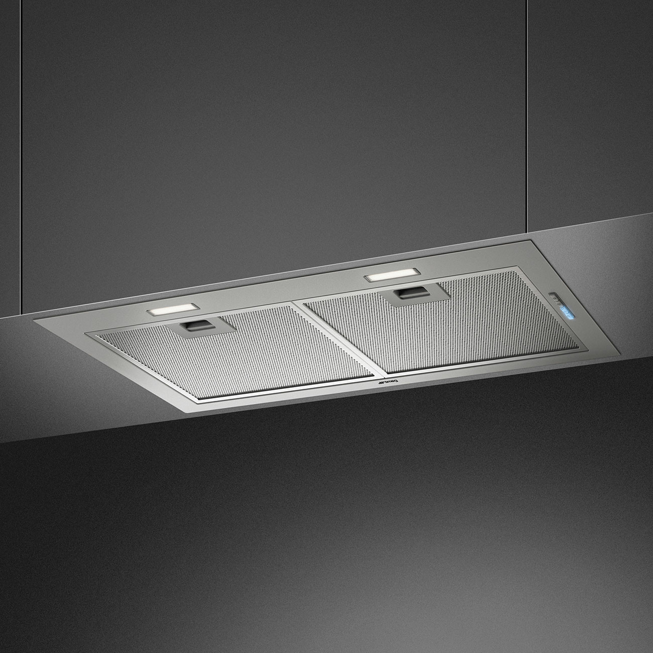 Una cappa in acciaio inossidabile con due luci e un filtro a rete, appesa a un soffitto grigio scuro.