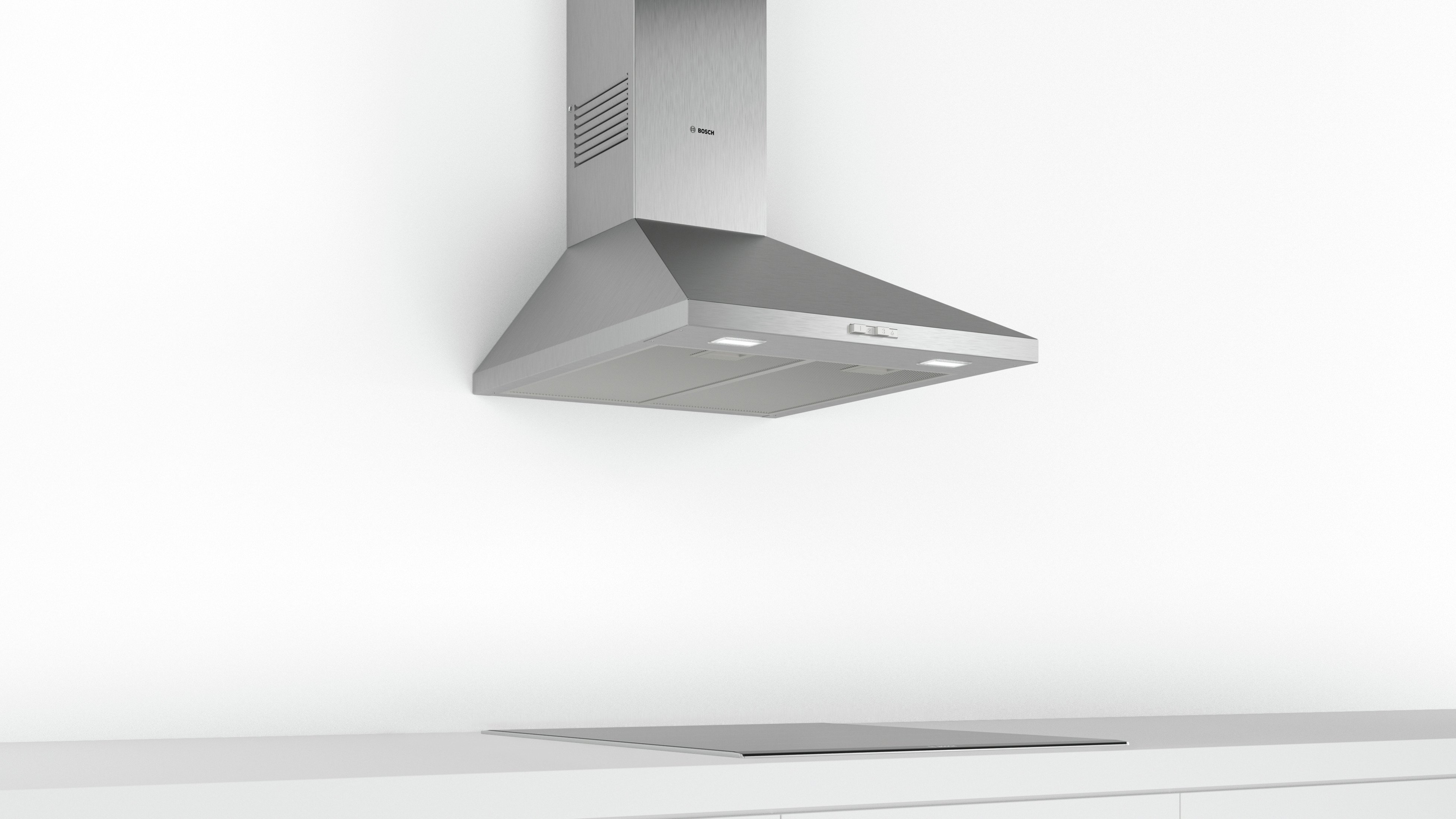 Cappa in acciaio inox montata su parete bianca sopra un piano cottura.