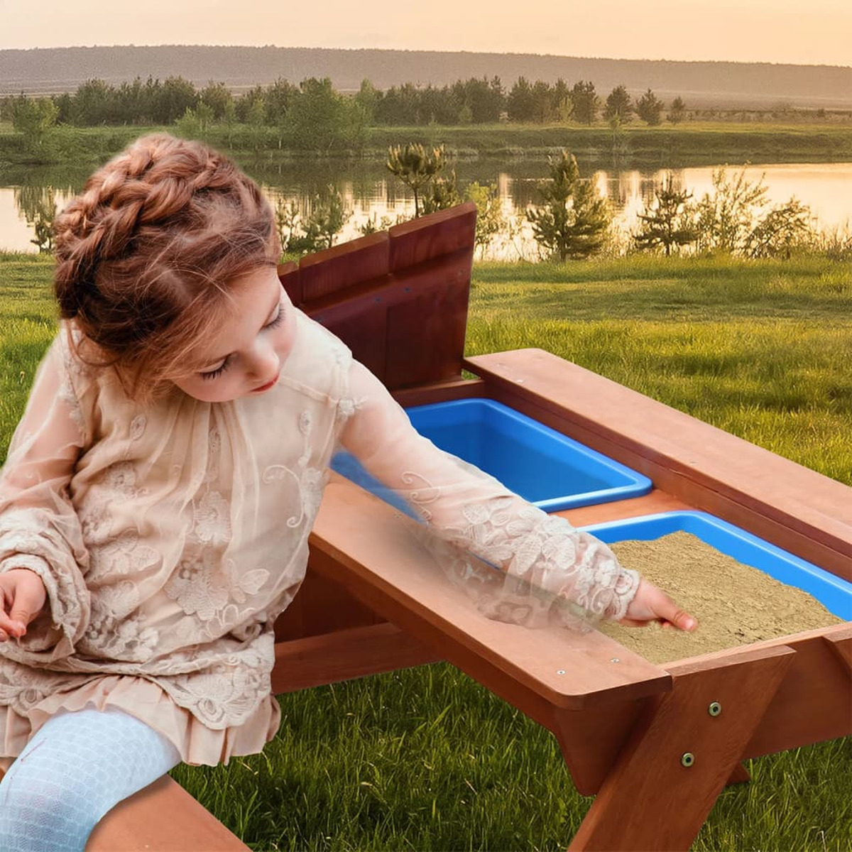 Ein Mädchen spielt in einem Sandkasten mit einem Holztisch, im Hintergrund ein See.
