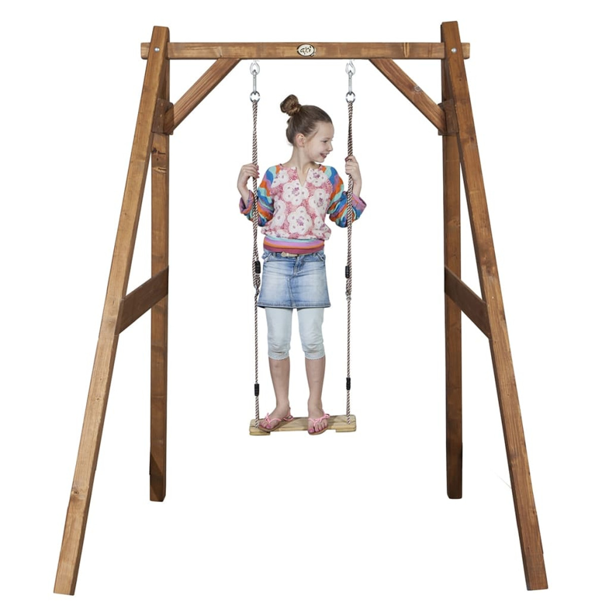 Ein junges Mädchen schwingt auf einer Holzschaukel und lächelt.