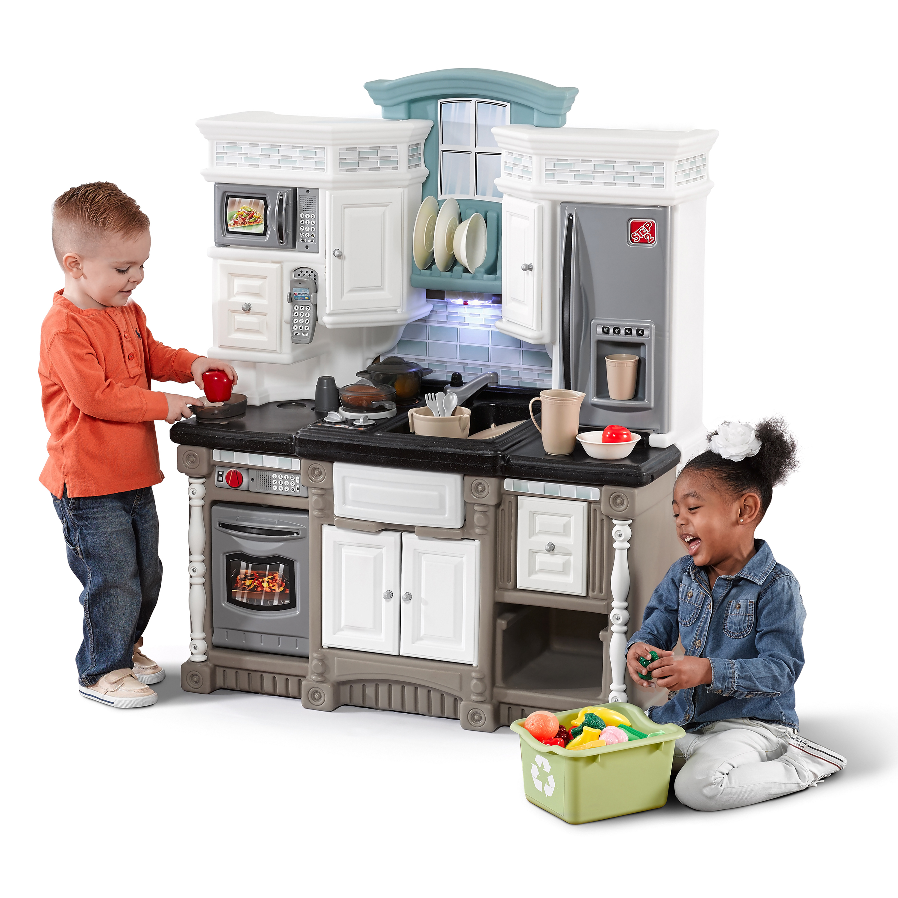 Kinder spielen mit einem Spielzeugküchenset. Enthält Backofen, Kühlschrank und Spielzeugessen.