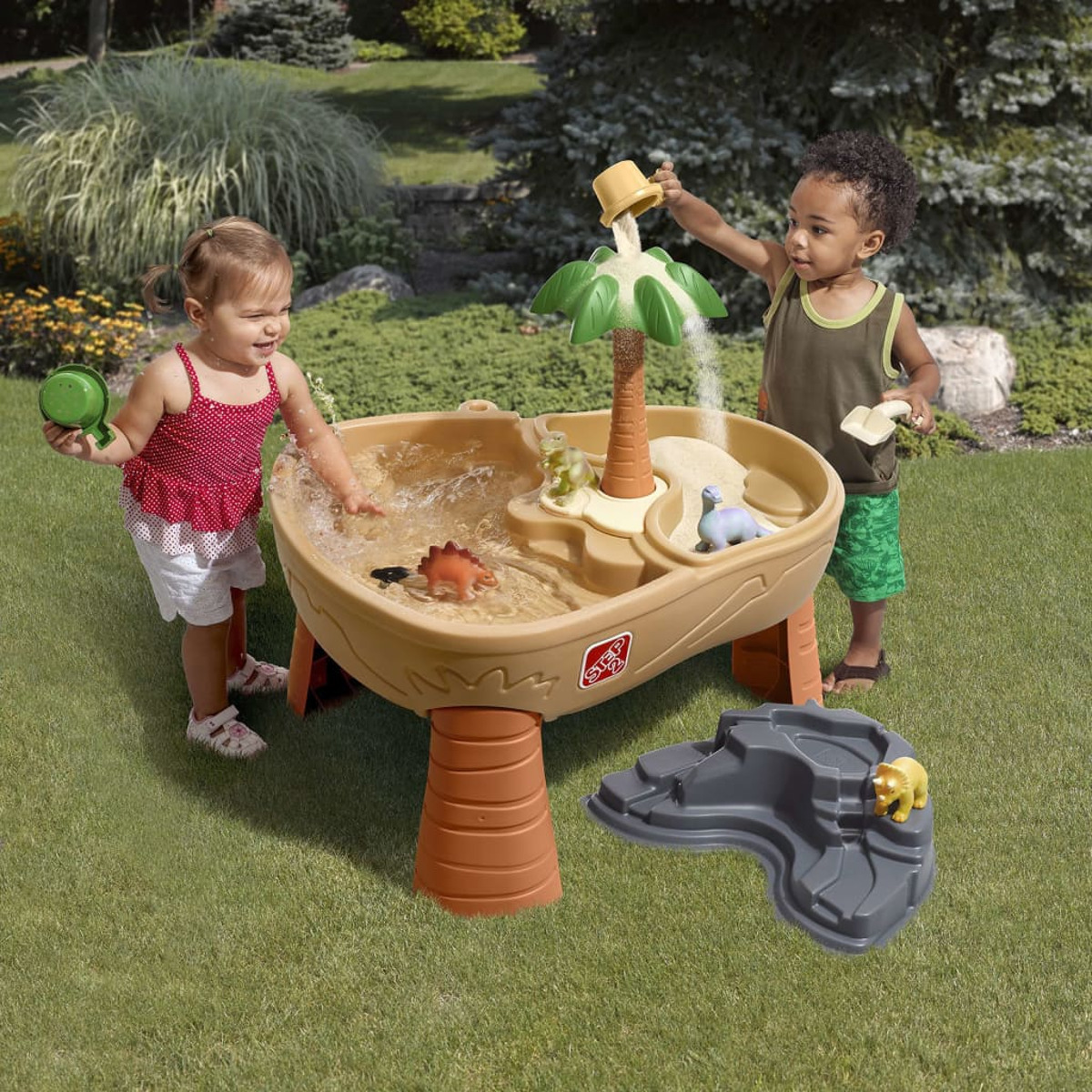 Zwei Kinder spielen mit einem Wassertisch mit Dinosauriern.