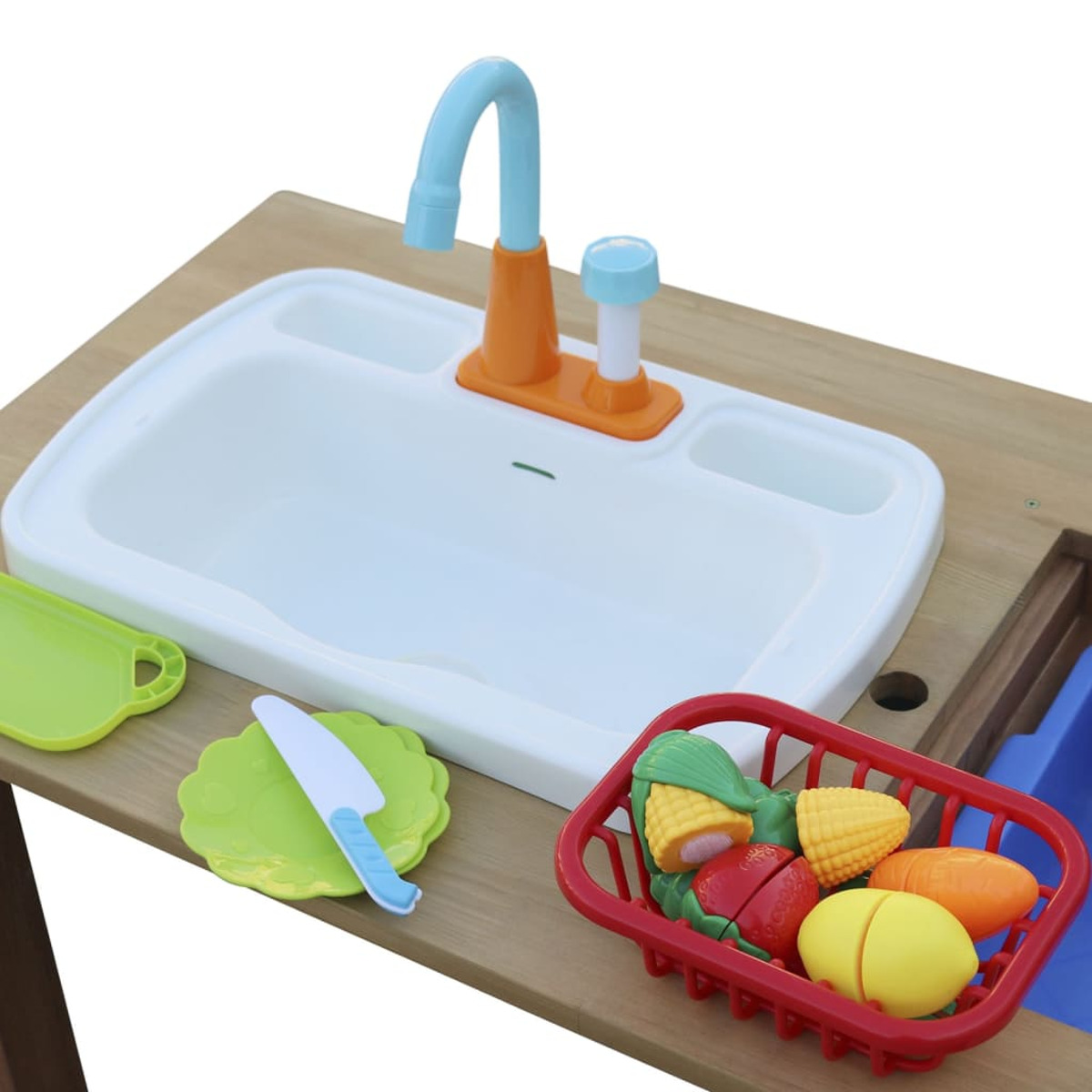Spielzeugküchenspüle mit Zubehör. Roter Korb mit Spielzeuggemüse und ein grünes Schneidebrett und Messer.