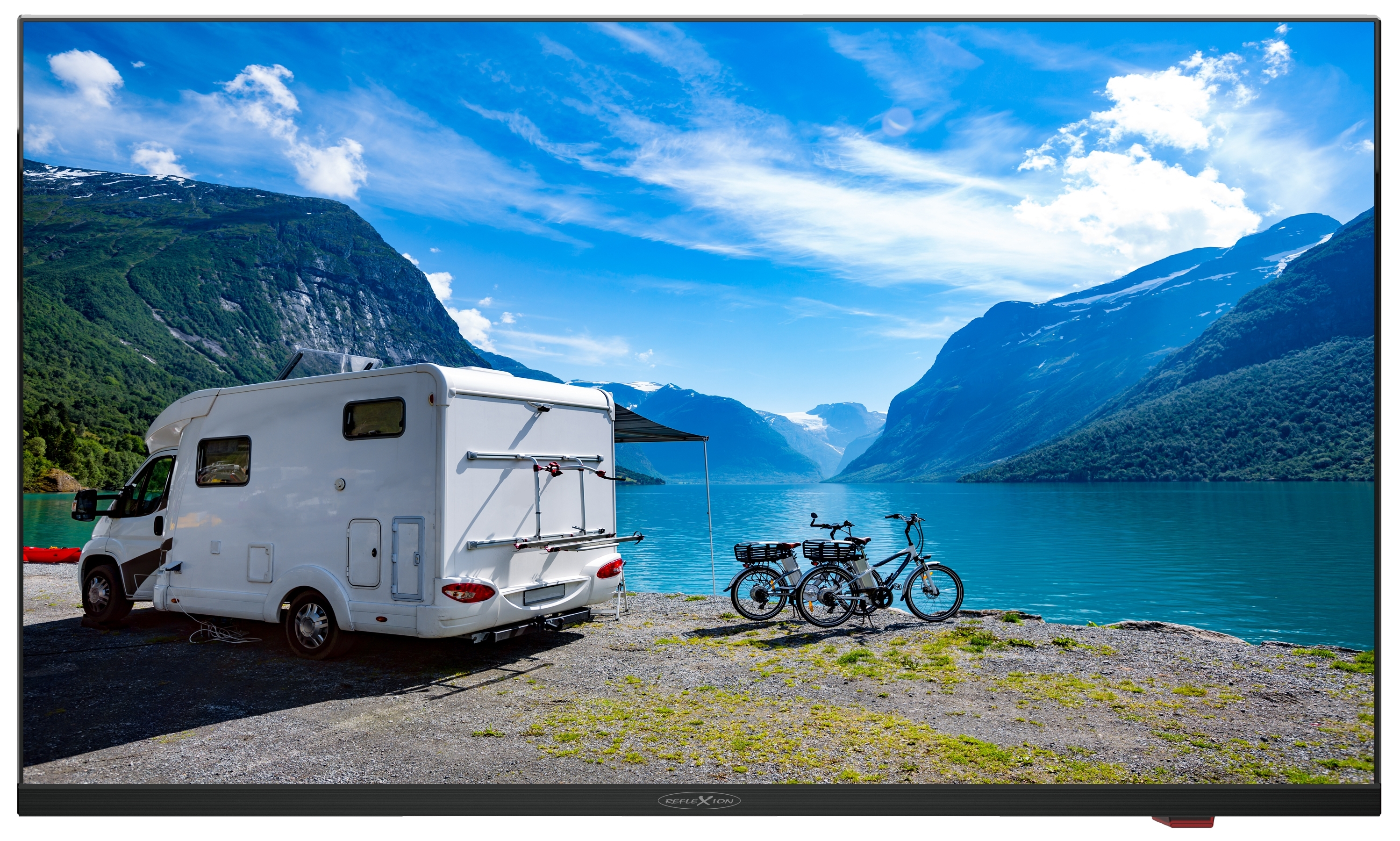 Wohnmobil geparkt in der Nähe eines Sees mit Bergen und blauem Himmel.