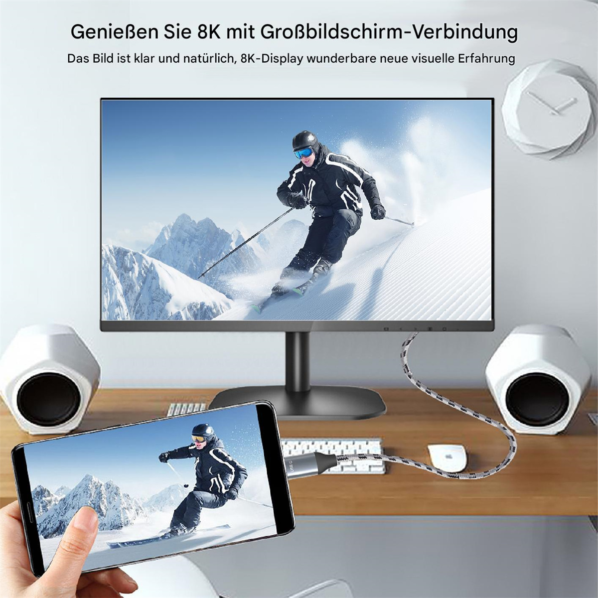 Eine Person hält ein Telefon, das einen Skifahrer auf einem Monitor anzeigt, der über ein Kabel verbunden ist.